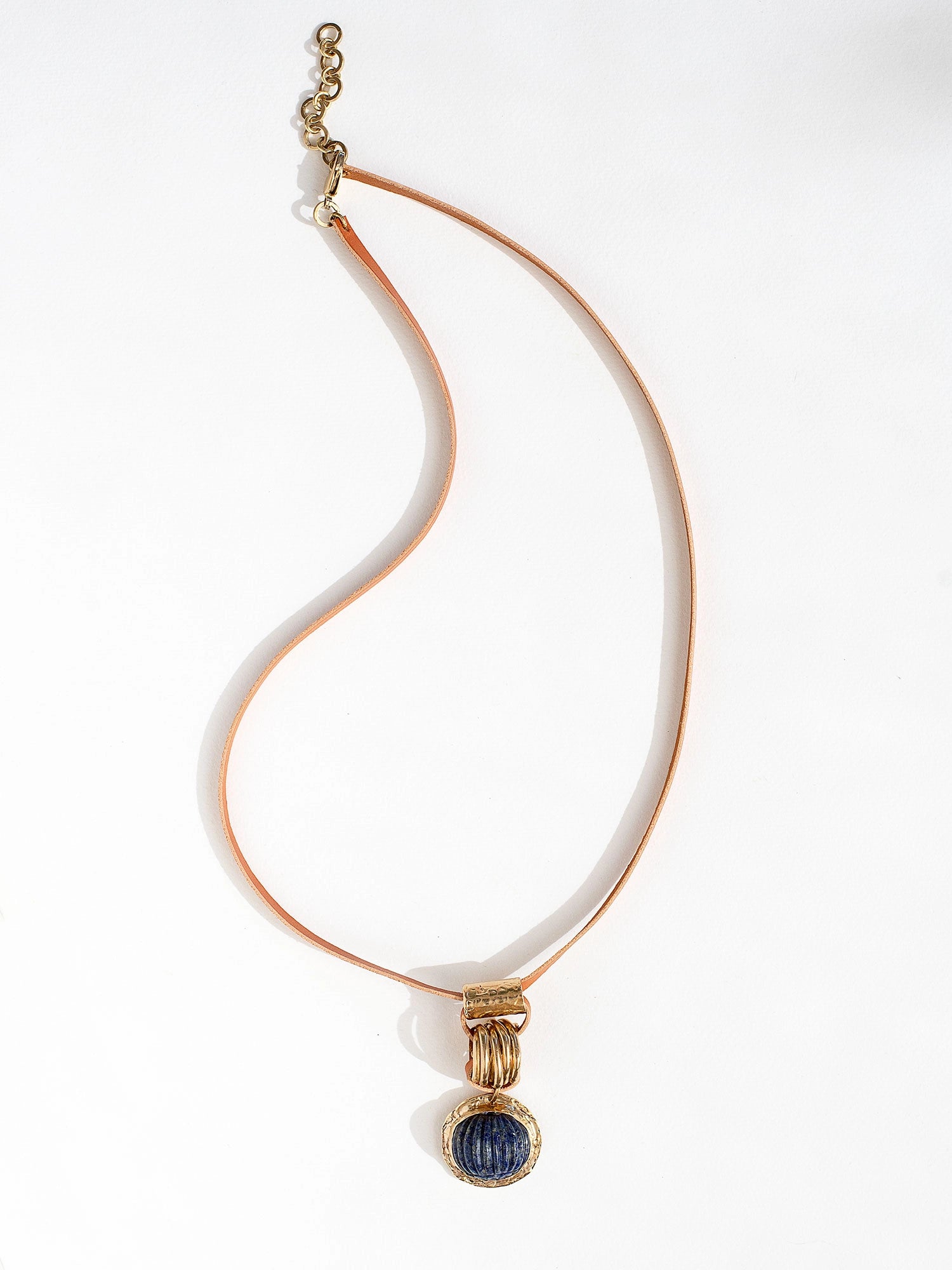 A tan leather long necklace with a brass and lapis lazuli circular pendant by Canadian jewelry designer Michelle Ross