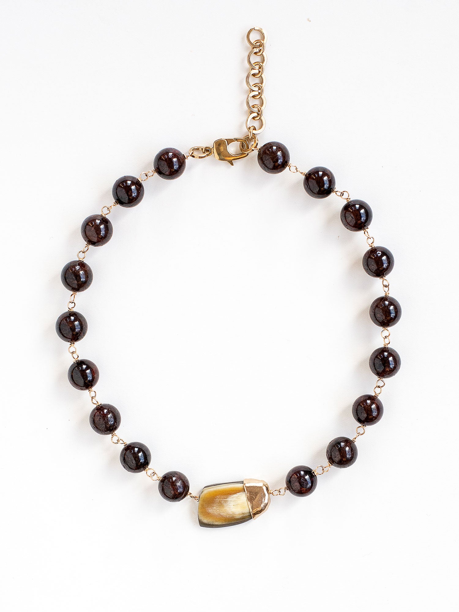 Beaded garnet collar necklace with a large horn pendant and brass details by Michelle Ross