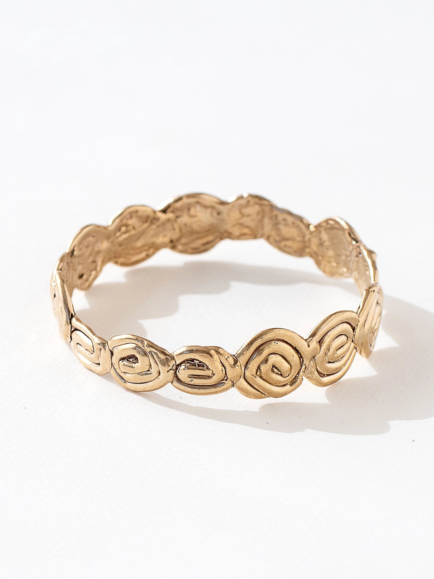 A solid brass bangle bracelet with swirl hand-formed details by Canadian jewelry designer Michelle Ross