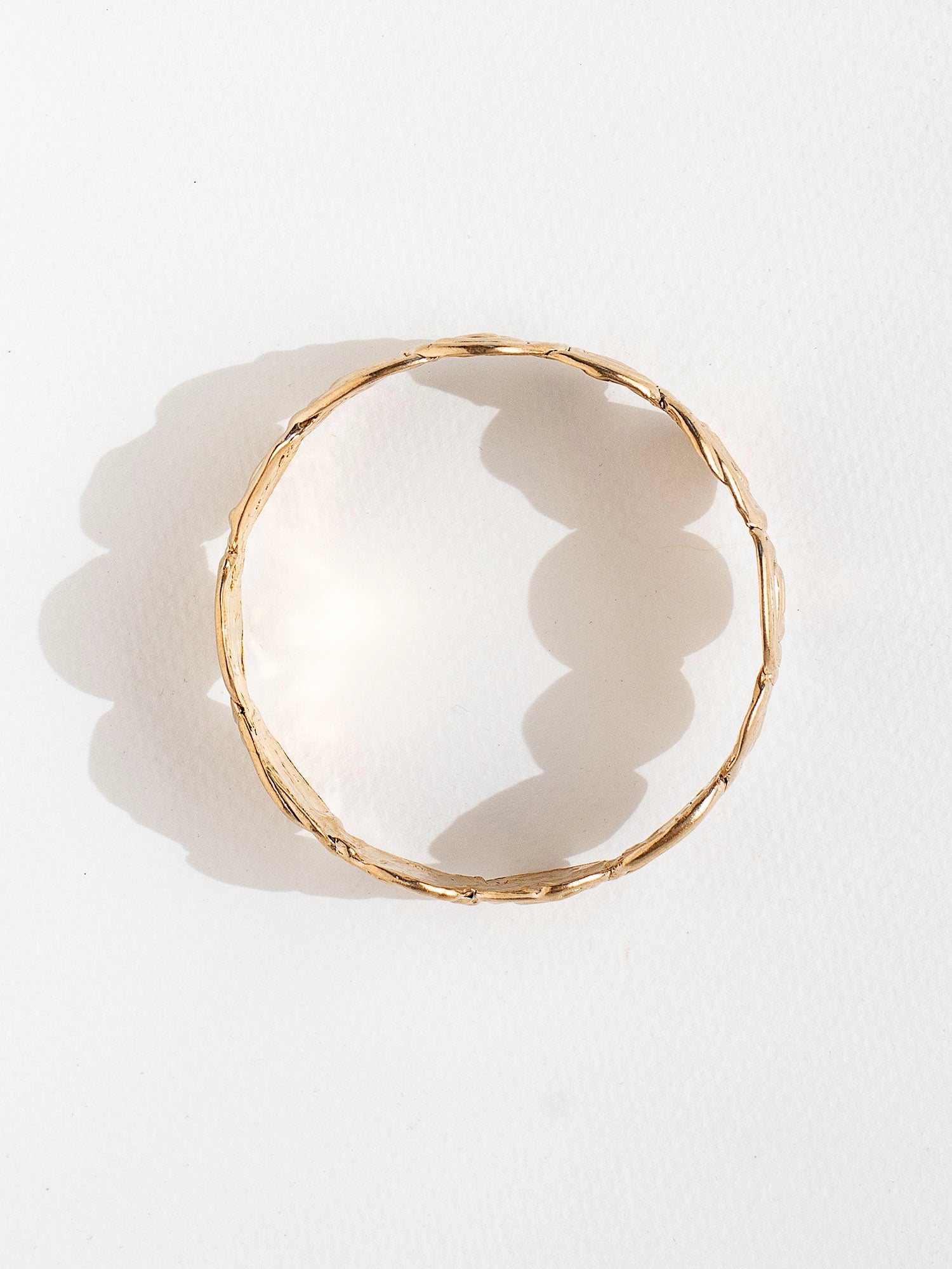A solid brass bangle bracelet with swirl hand-formed details by Canadian jewelry designer Michelle Ross