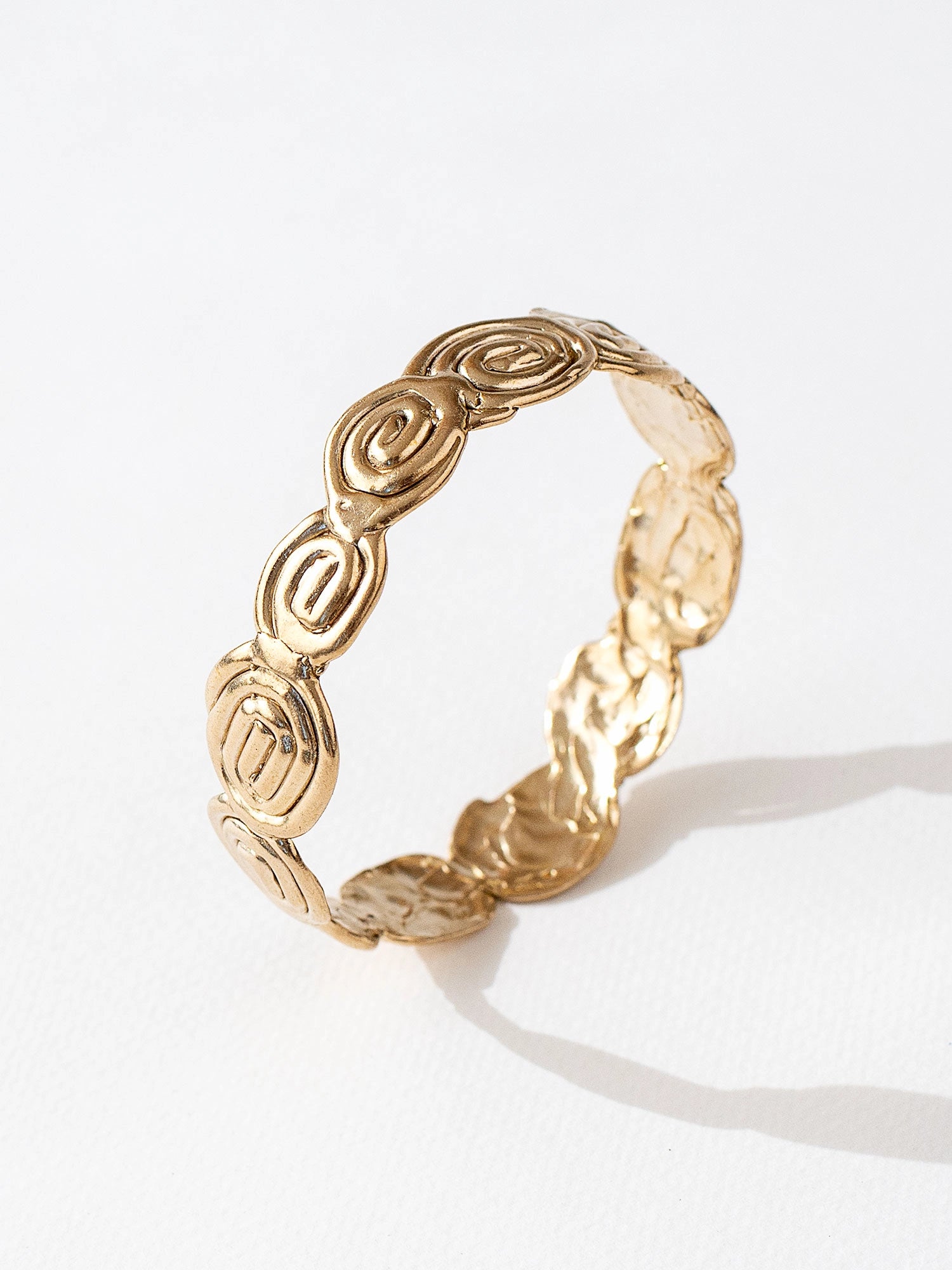 A solid brass bangle bracelet with swirl hand-formed details by Canadian jewelry designer Michelle Ross