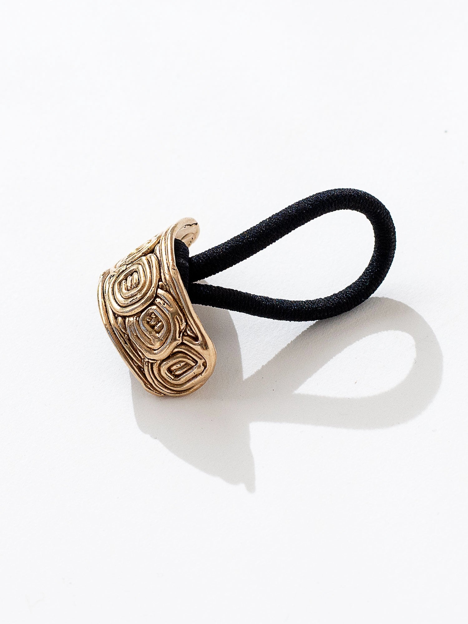 A brass solid hair tie with spiral scroll detail by Canadian jewelry designer Michelle Ross