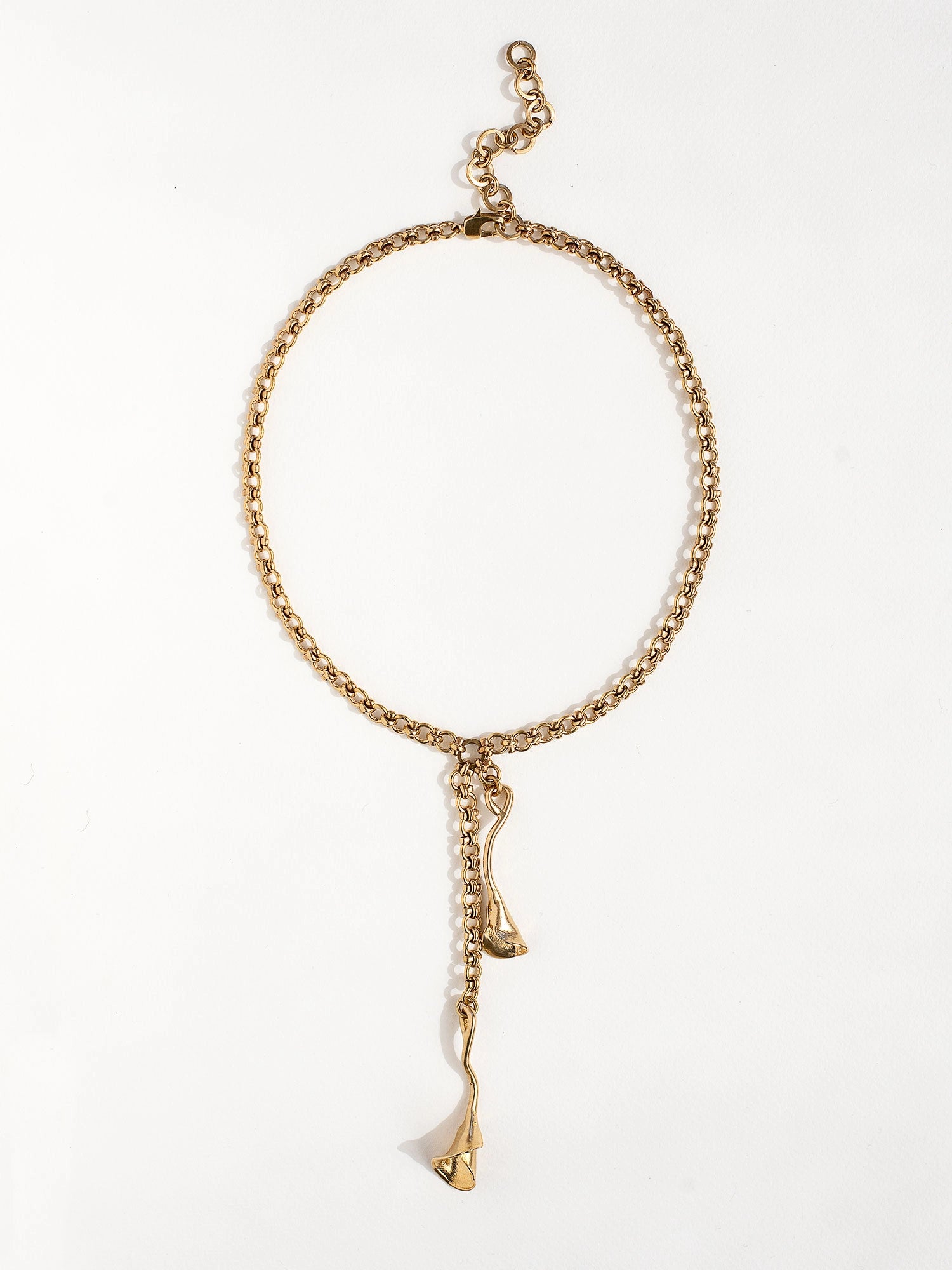 A woman wears a brass chain lariat necklace with sculptural floral pendant details by Canadian jewelry designer Michelle Ross