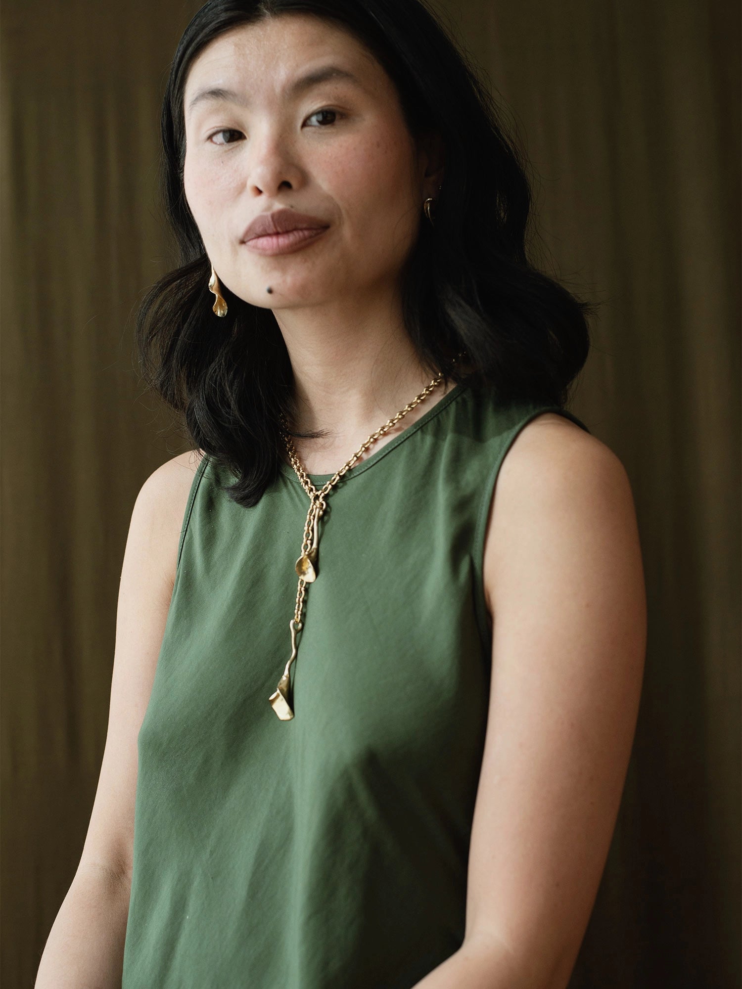 woman wearing abstract floral brass earrings and brass chain lariat necklace with abstract floral brass pendant by Canadian jeweller Michelle Ross