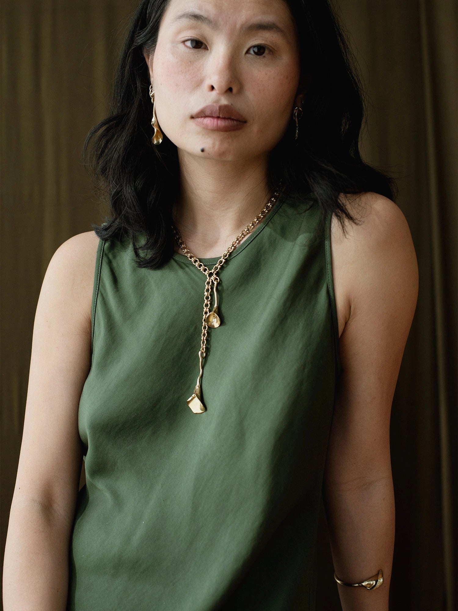 woman wearing abstract floral brass earrings and brass chain lariat necklace with abstract floral brass pendant by Canadian jeweller Michelle Ross