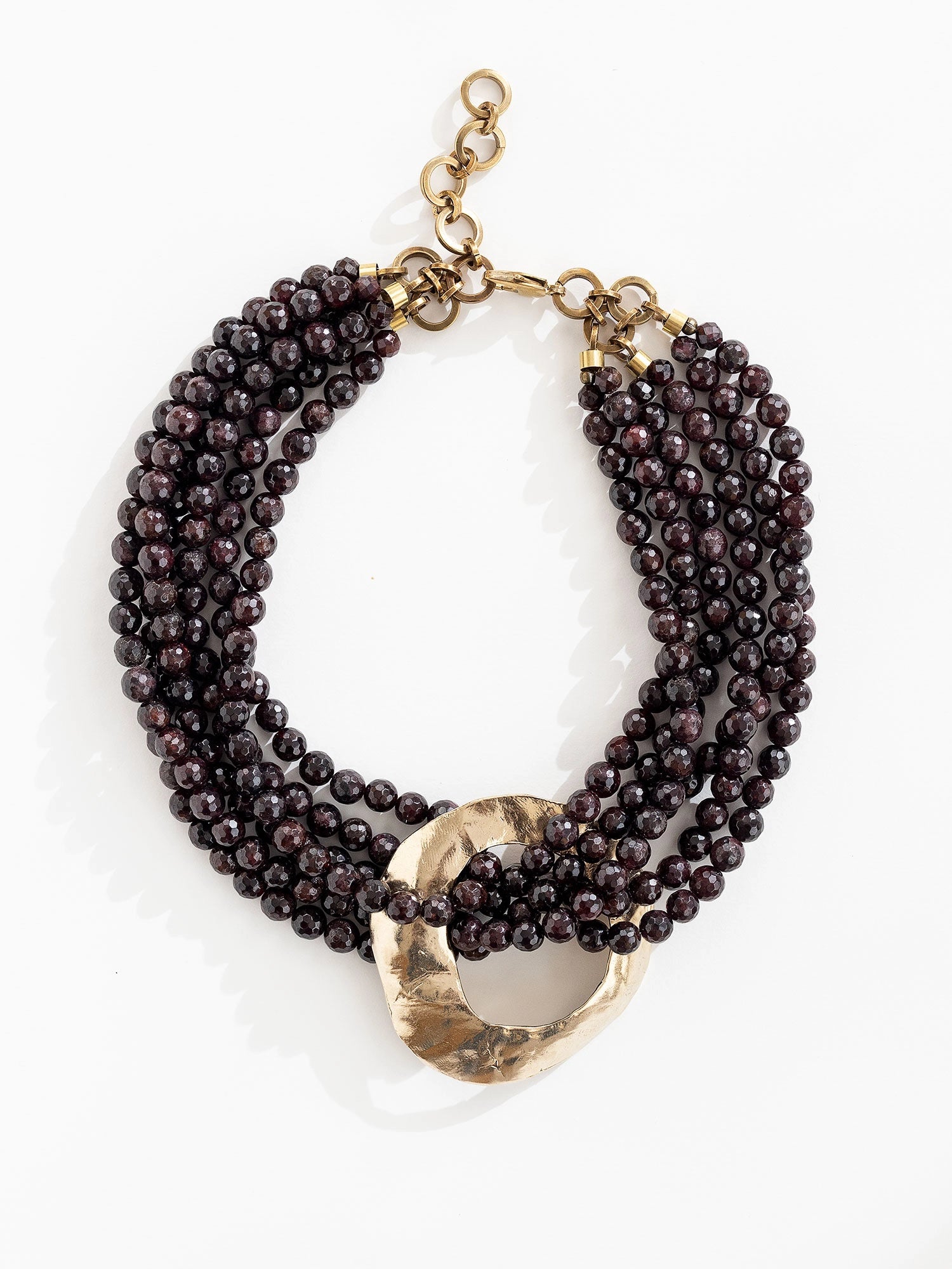 Multistrand beaded garnet necklace with a large central brass pendant by Michelle Ross