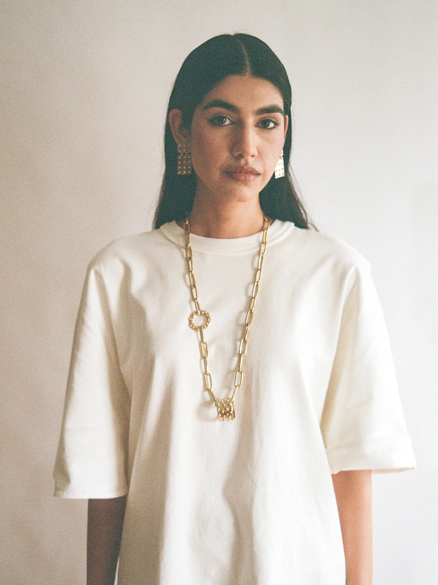 woman wears Lago Lightweight Rectangular Brass Statement Earrings by Michelle Ross