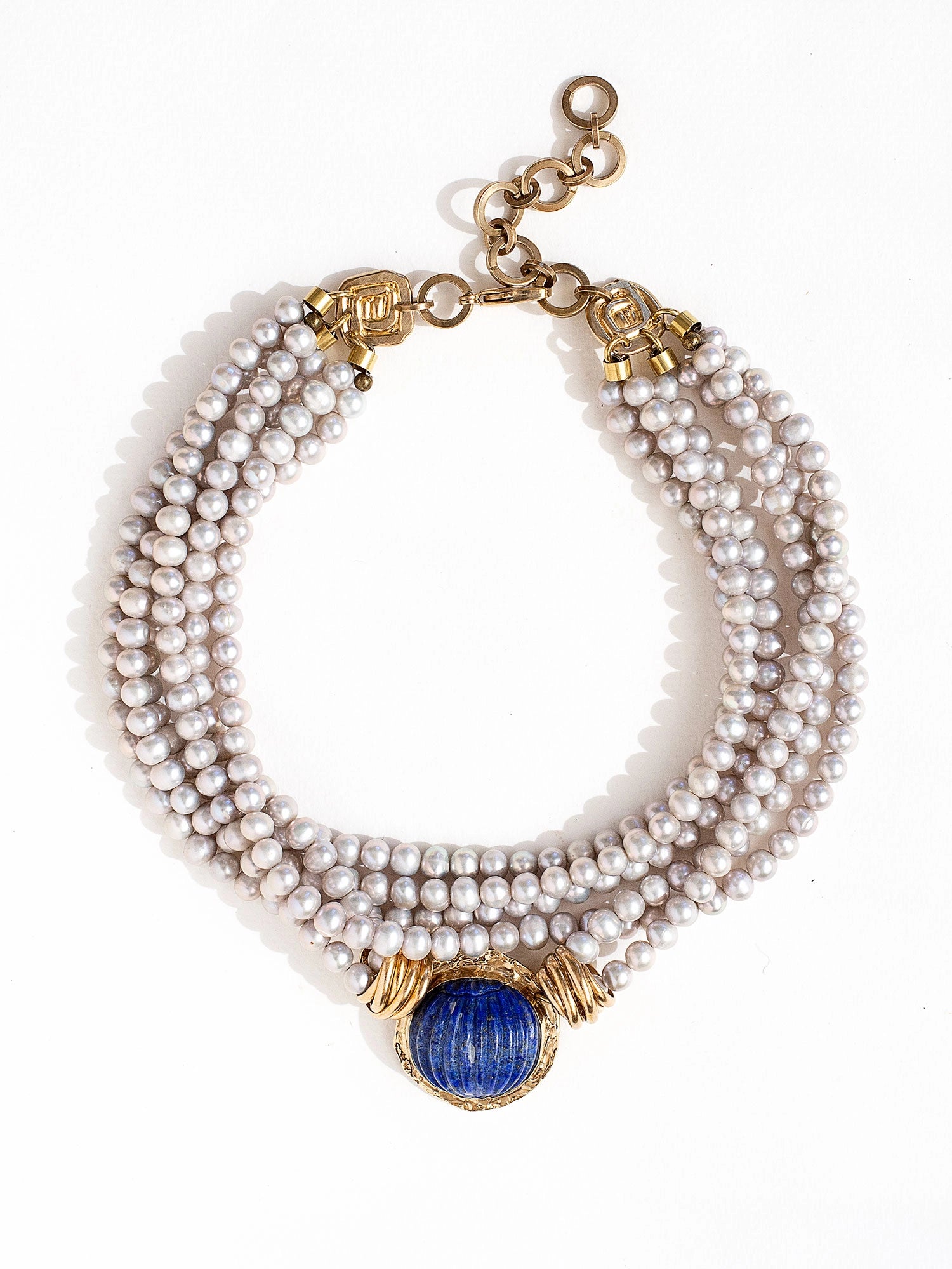 A multistrand silver pearl necklace with a large lapis lazuli and brass pendant with brass closure details by Canadian jewelry designer Michelle Ross