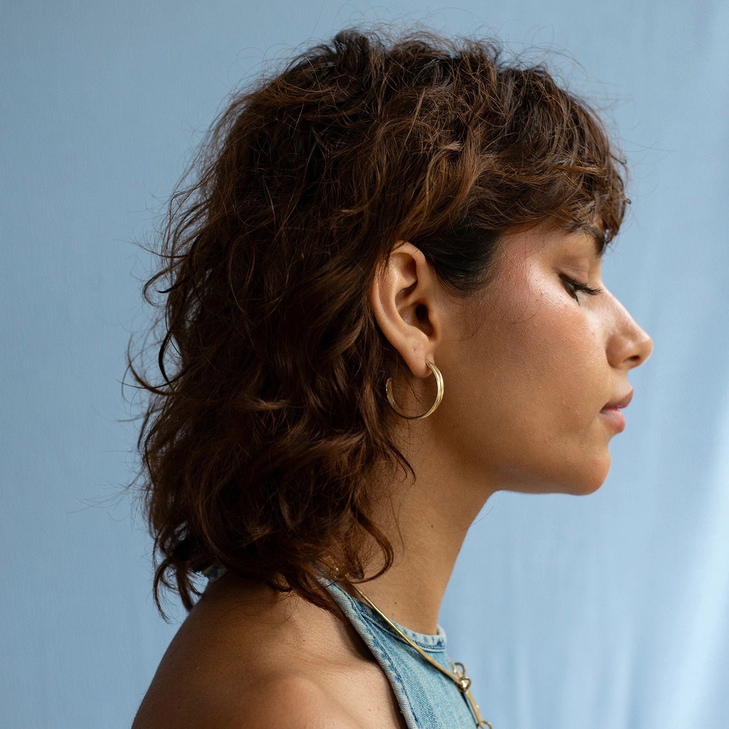 a woman wears gold brass hoop earrings by contemporary Canadian jewelry designer Michelle Ross