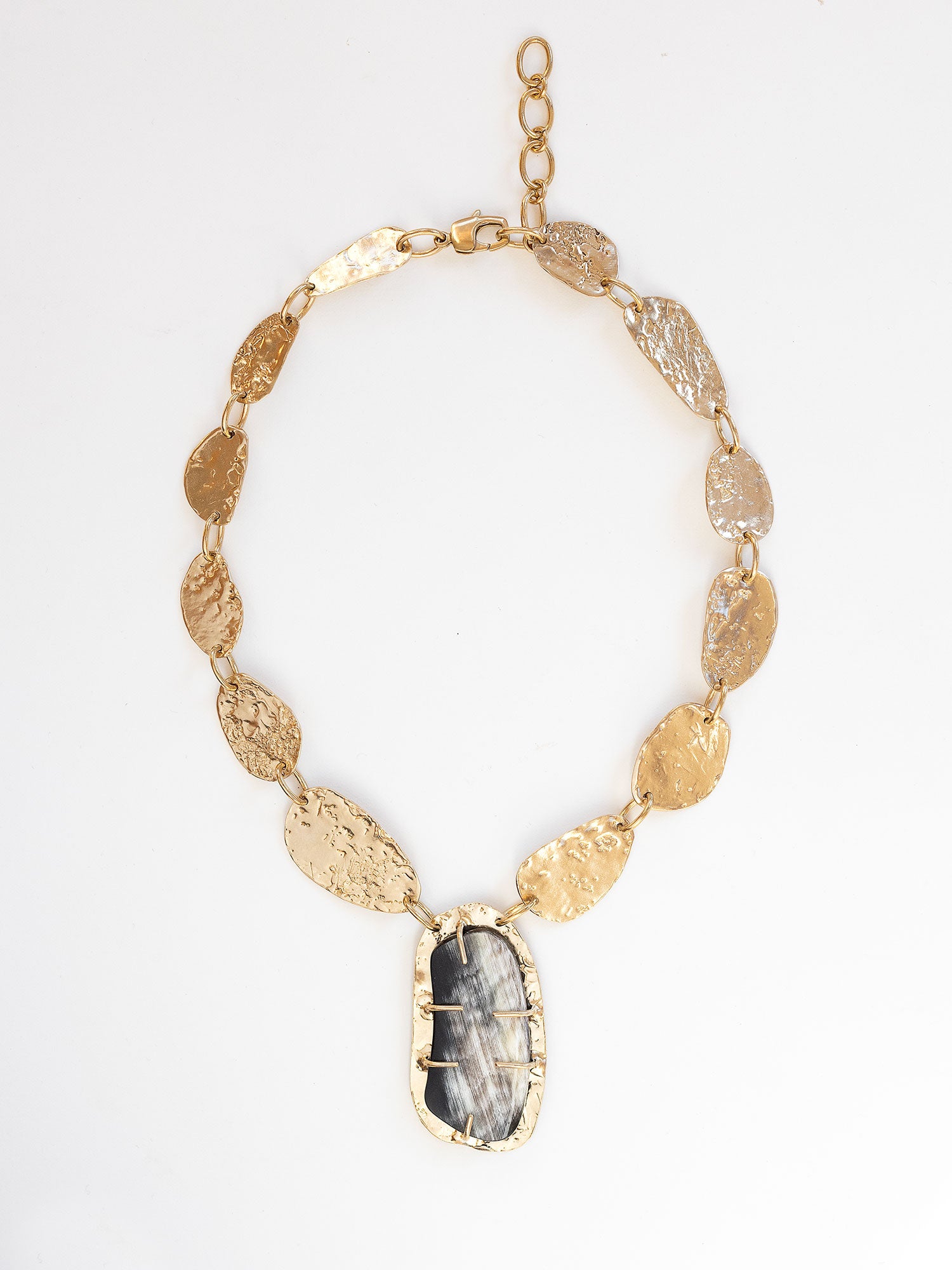 A brass statement necklace with hammered brass discs and a large central horn pendant by Michelle Ross