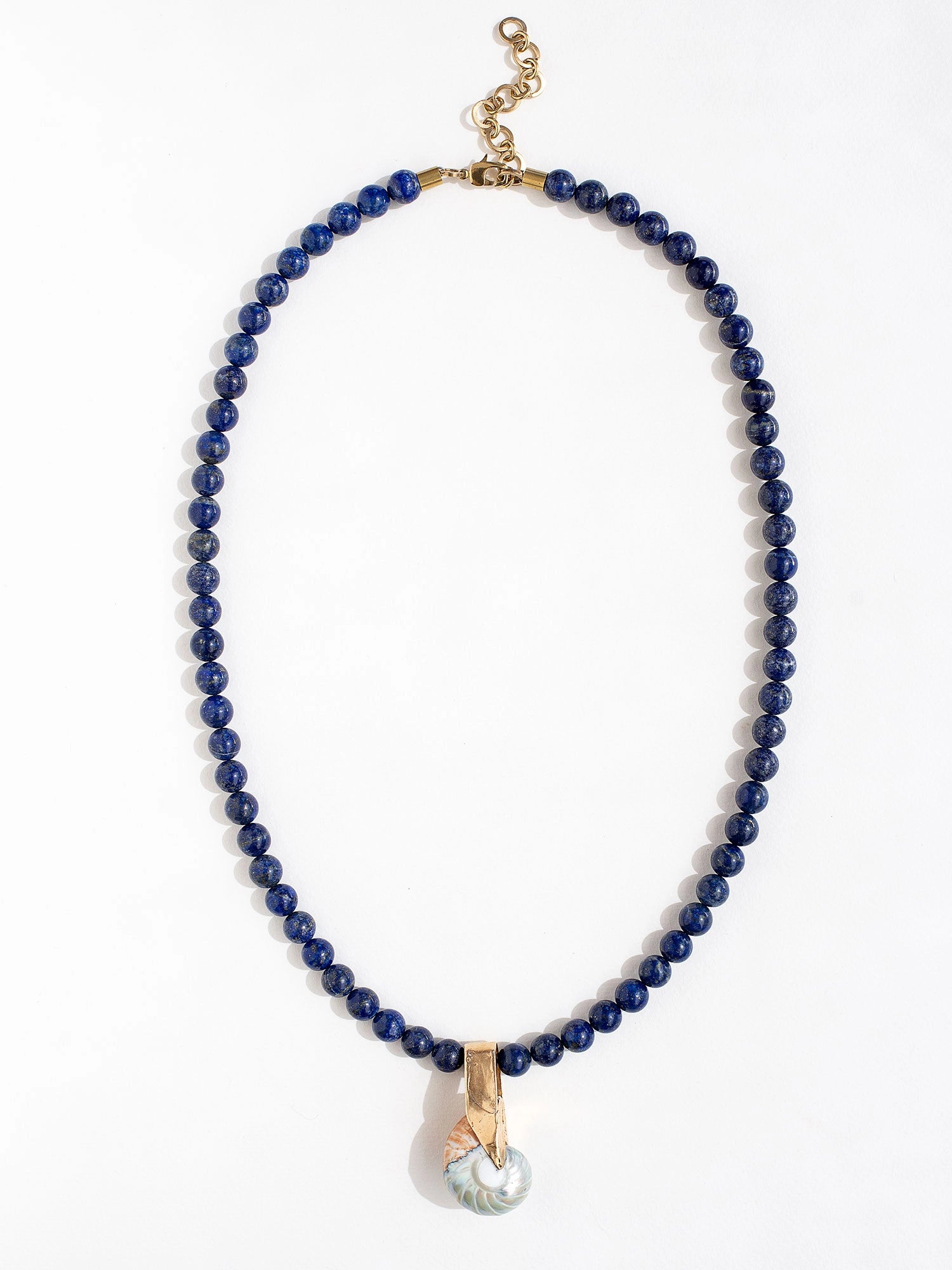 A lapis lazuli beaded necklace with large seashell and brass pendant by Canadian jewelry designer Michelle Ross