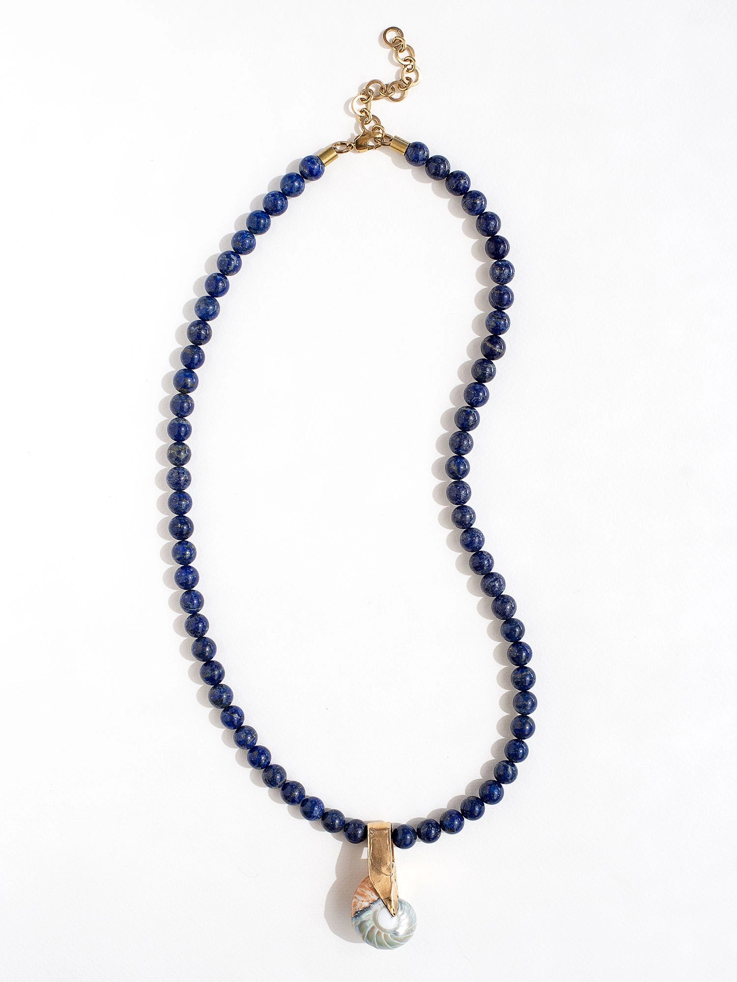 A lapis lazuli beaded necklace with large seashell and brass pendant by Canadian jewelry designer Michelle Ross