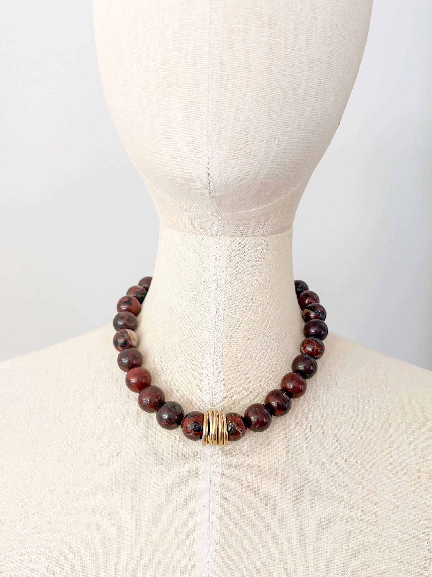 A beaded necklace made from red jasper stone beads with hand formed brass details by Canadian Jewelry Designer Michelle Ross