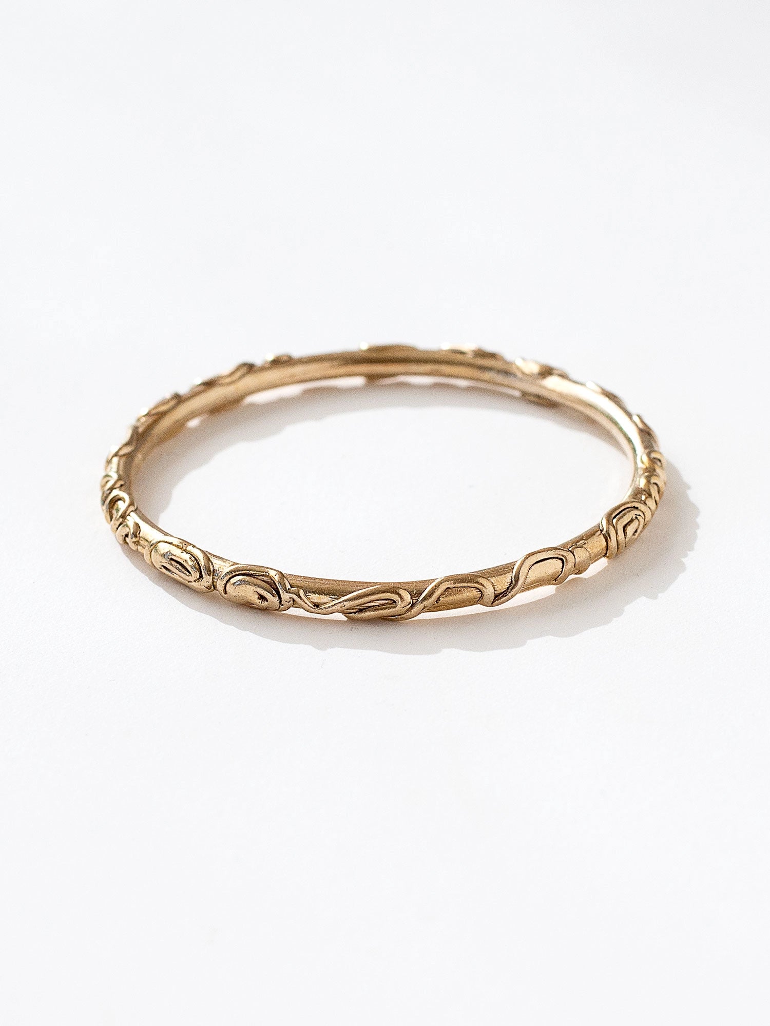 A solid brass bangle bracelet with spiral scrollwork details by Canadian jewelry designer Michelle Ross
