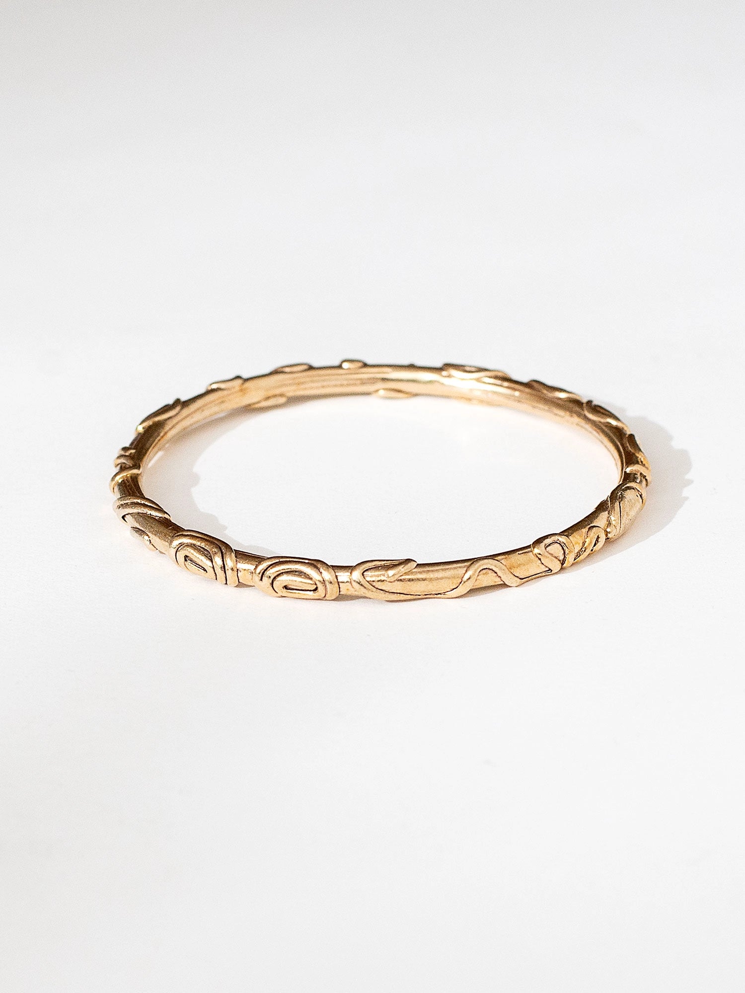 A solid brass bangle bracelet with spiral scrollwork details by Canadian jewelry designer Michelle Ross