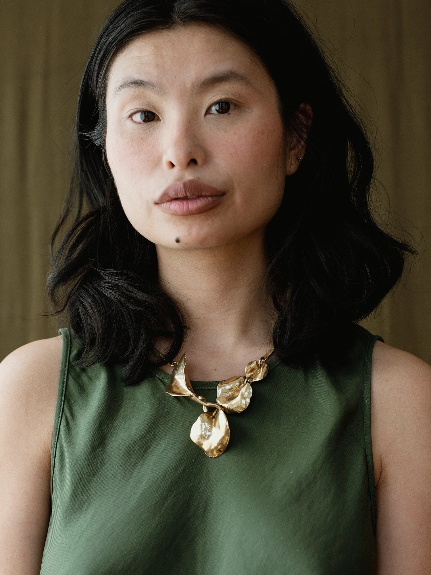 a woman wears a brass statement collar necklace with abstract floral sculptural designs by Canadian designer Michelle Ross