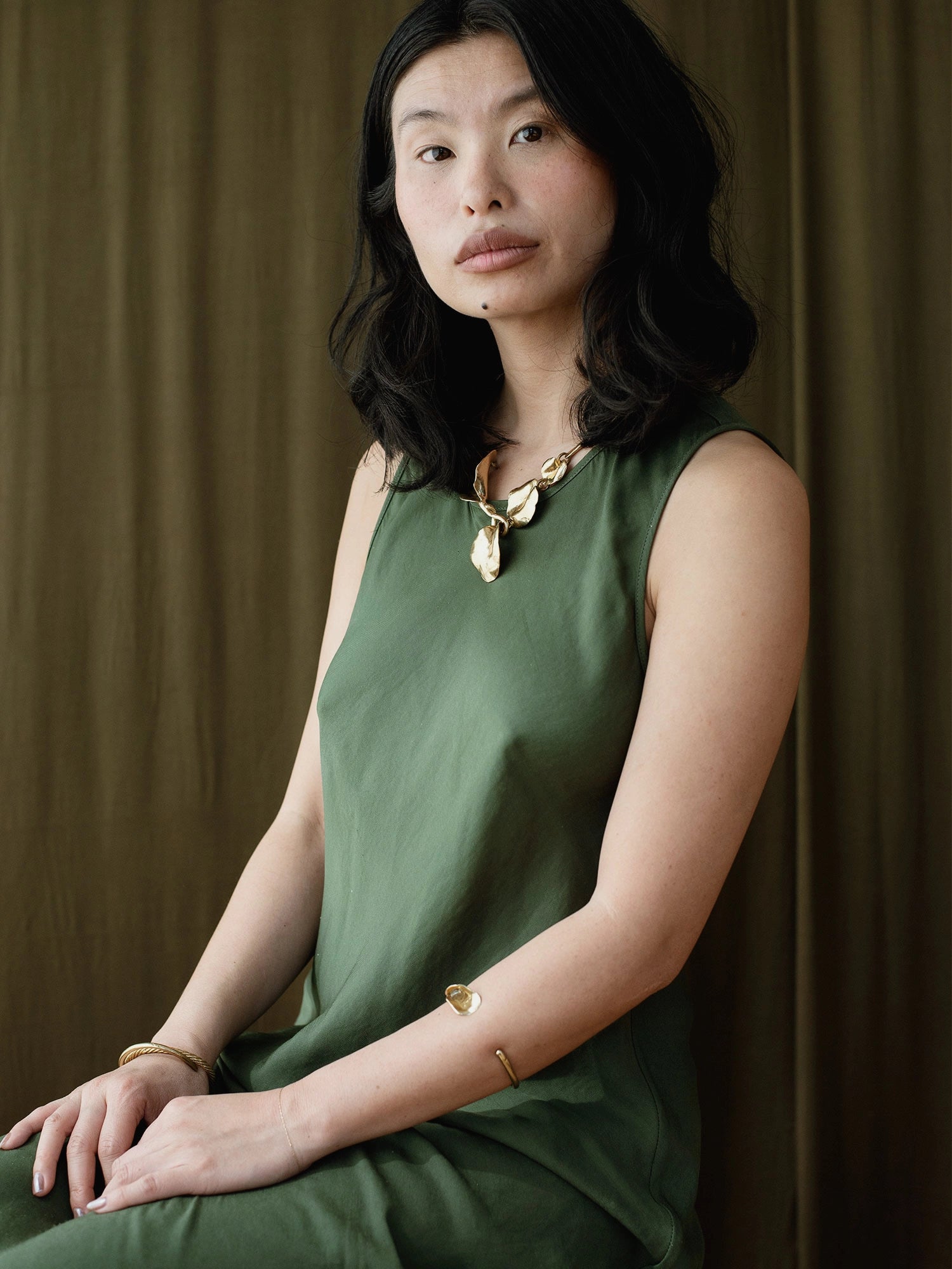 a woman wears a brass statement collar necklace with abstract floral sculptural designs by Canadian designer Michelle Ross