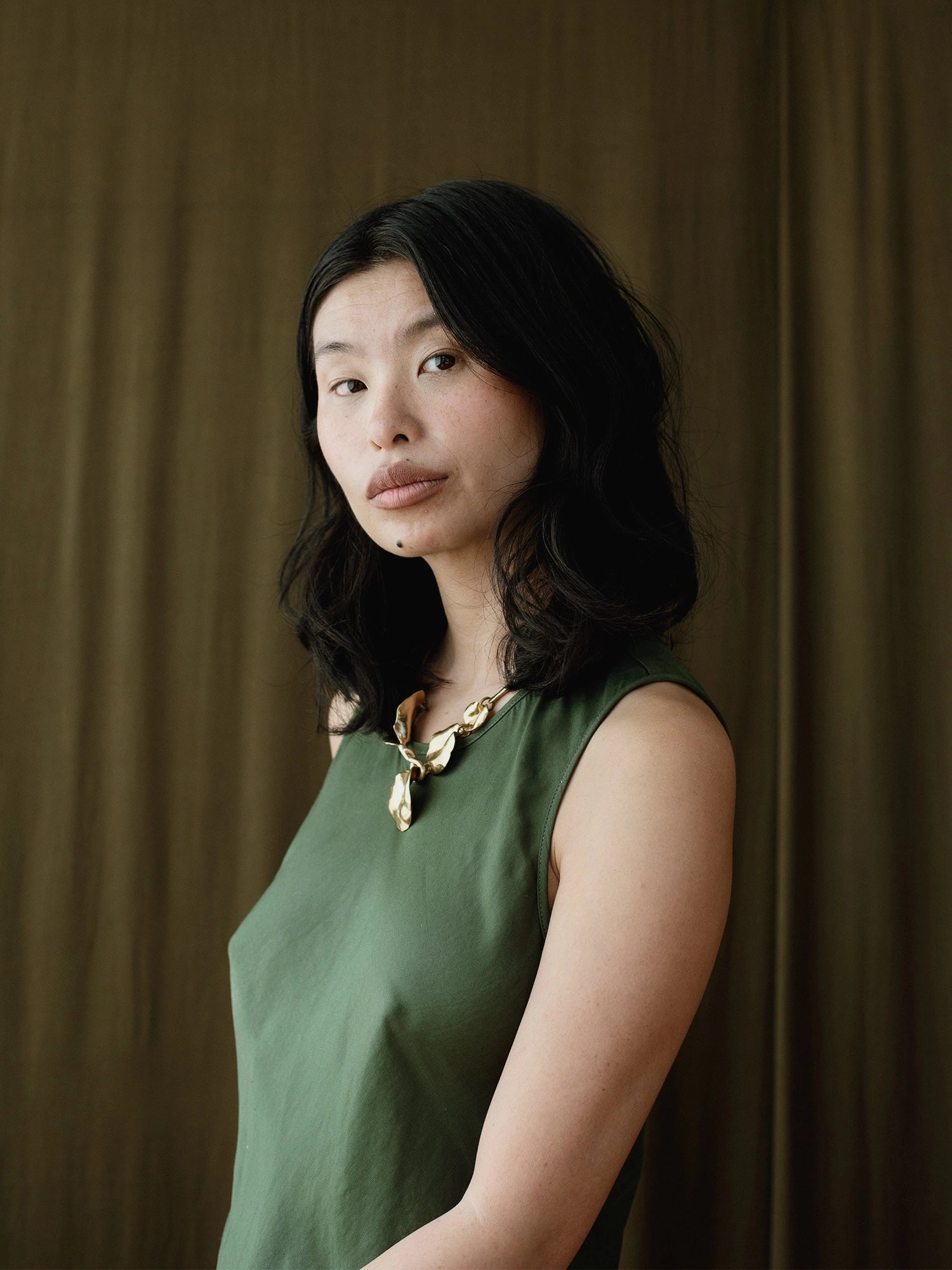a woman wears a brass statement collar necklace with abstract floral sculptural designs by Canadian designer Michelle Ross