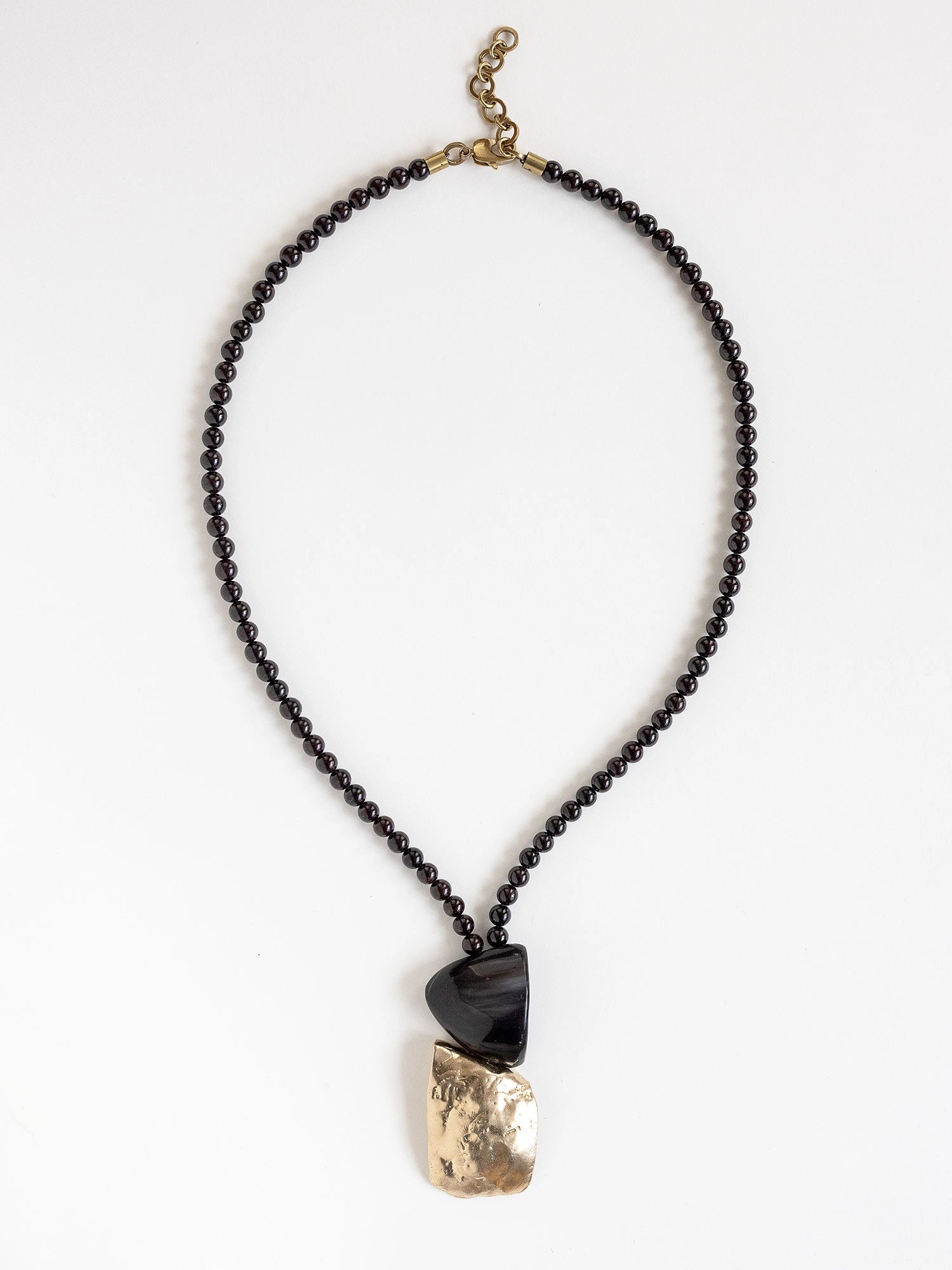 Necklace with garnet beads and a horn and brass pendant by Canadian designer Michelle Ross
