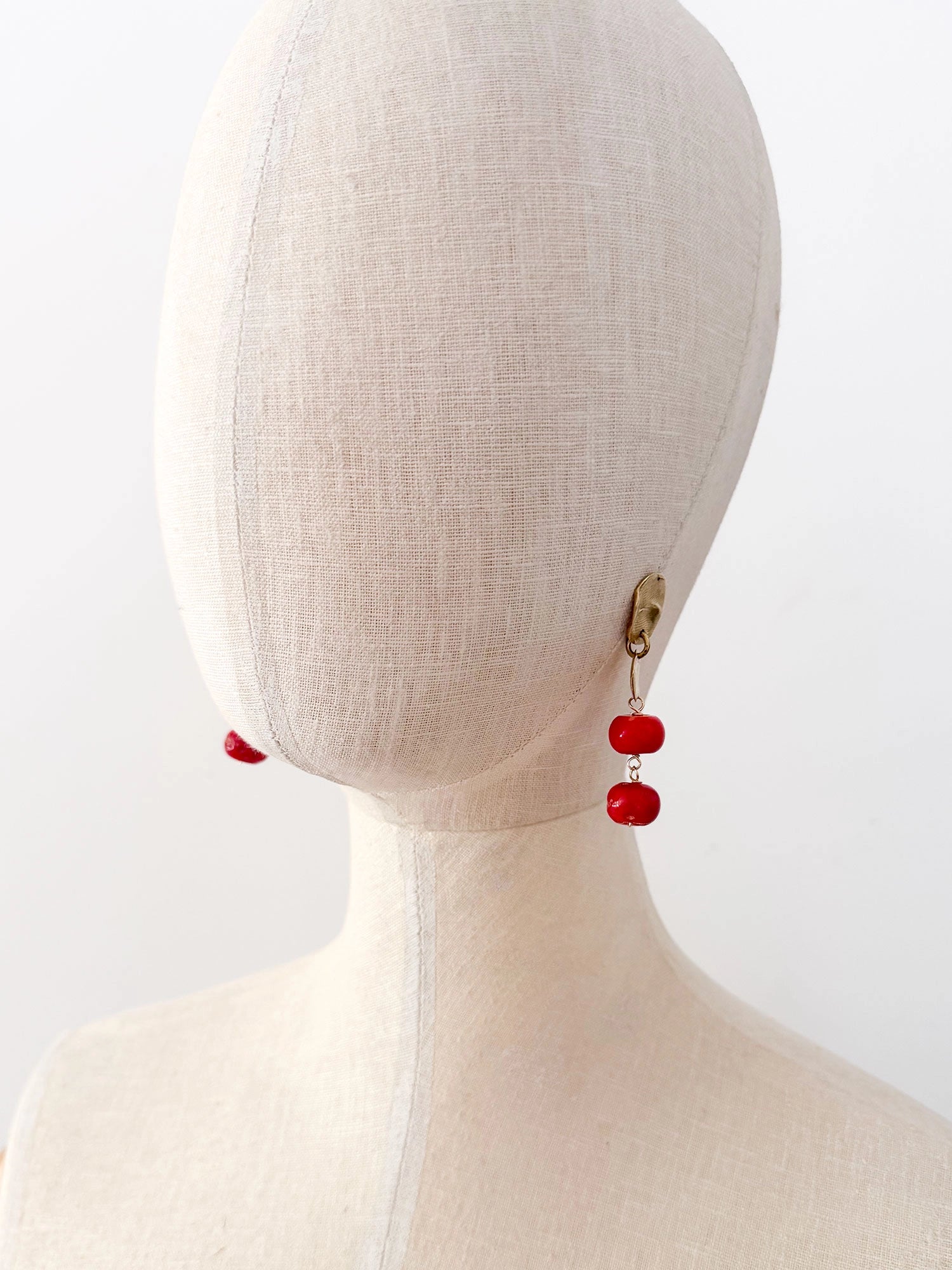A pair of brass and red drop coral beaded dangly earrings by Canadian jewelry designer Michelle Ross