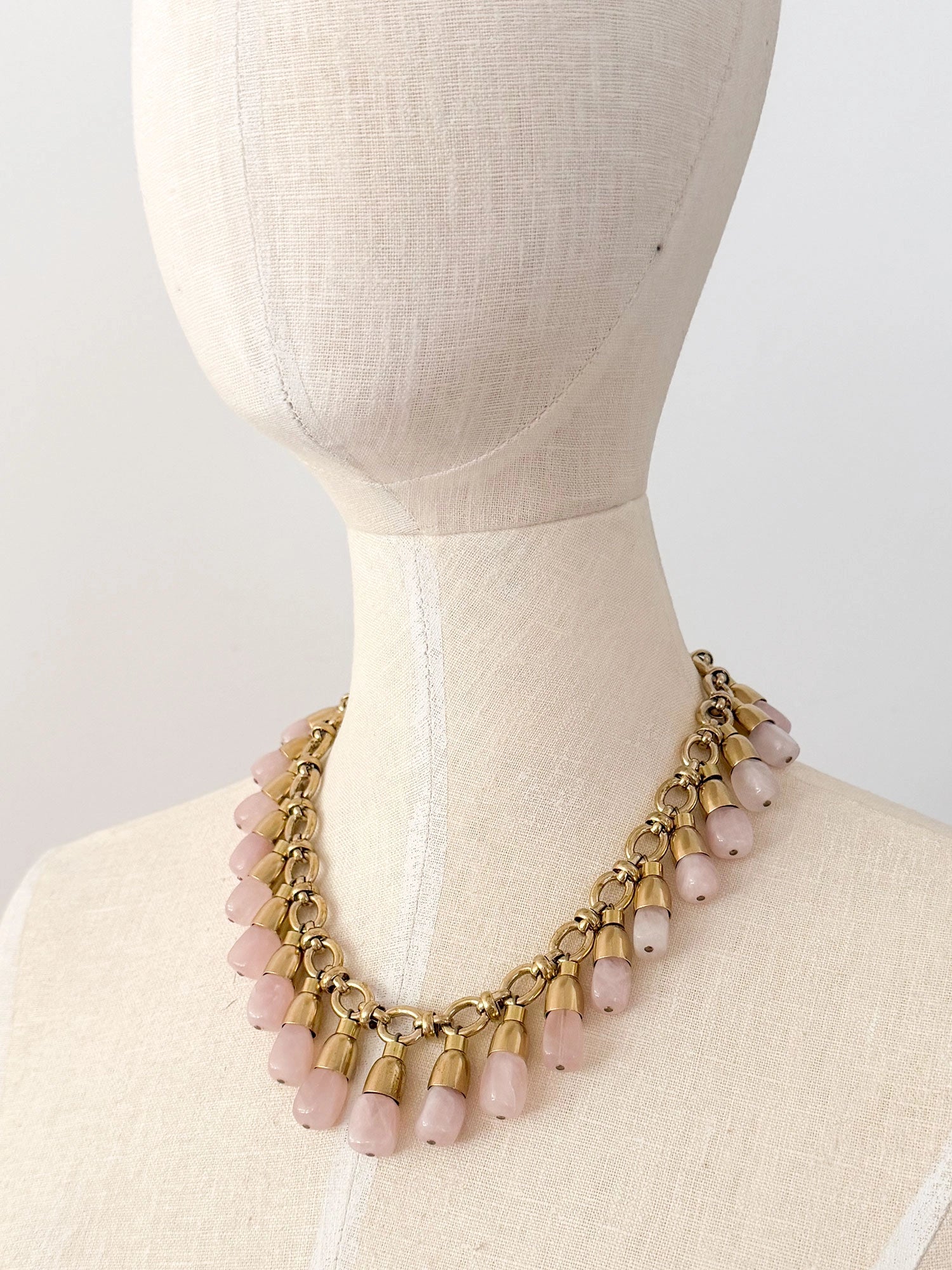A statement collar necklace featuring a brass chain and links with dangling rose quartz beads by Canadian designer Michelle Ross