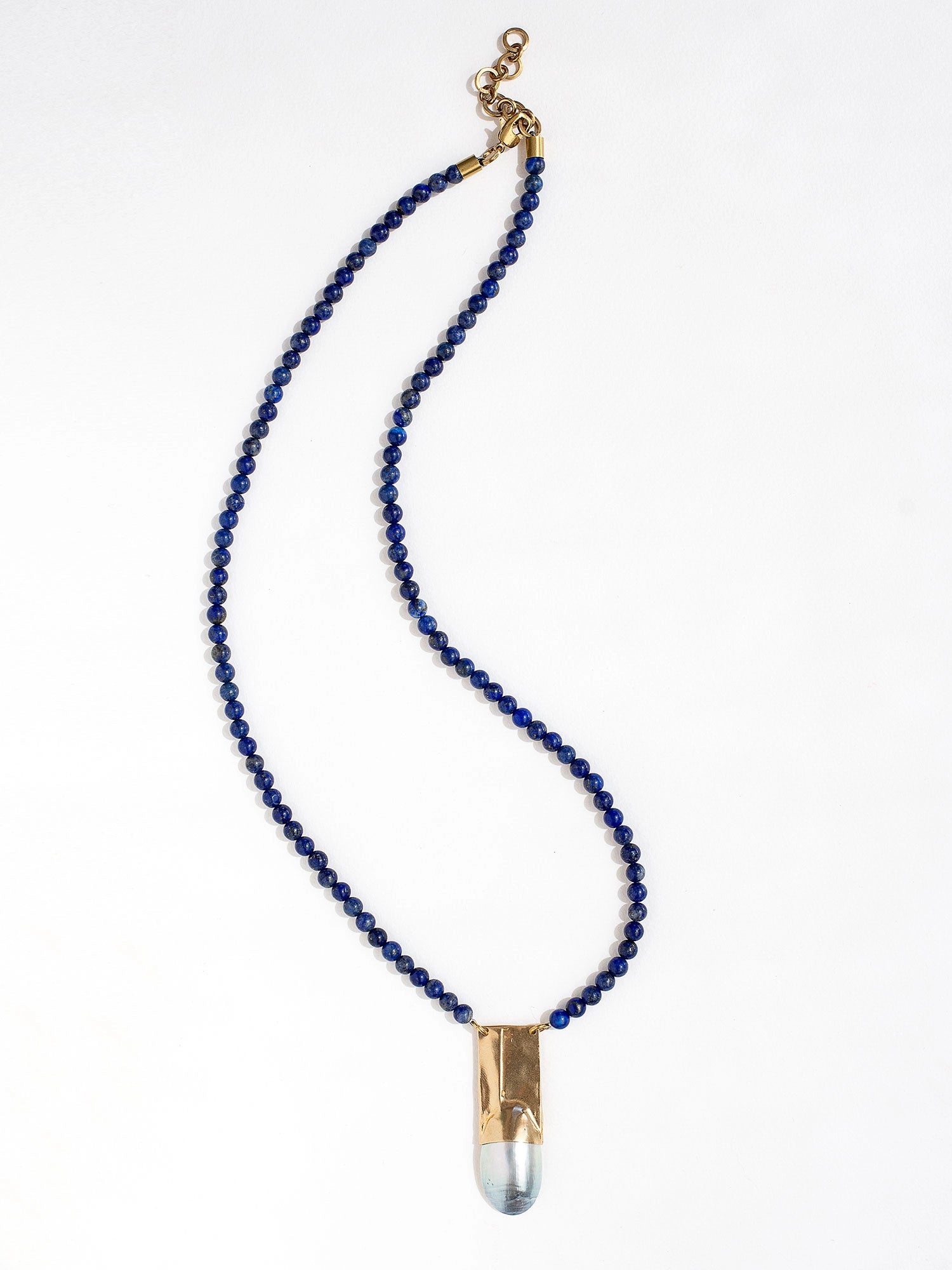 A lapis lazuli beaded necklace with a large statement mother of pearl and brass pendant by Canadian jewellery designer Michelle Ross