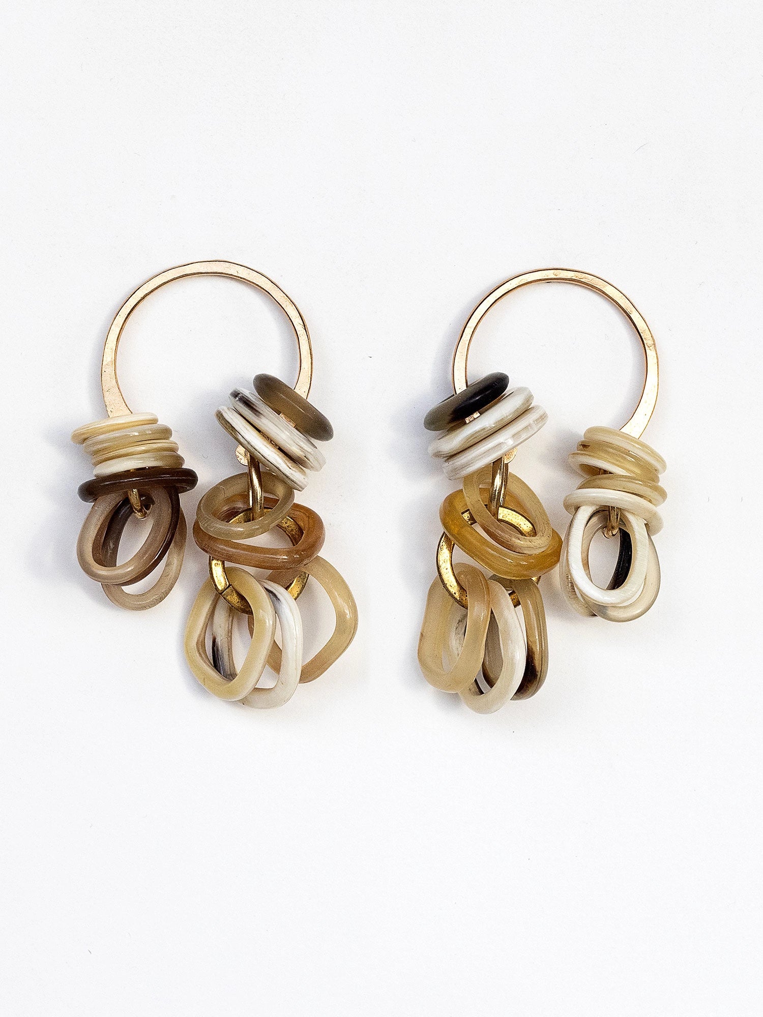 Pair of dangly brass earrings with multiple horn rings in gold, brown, and white