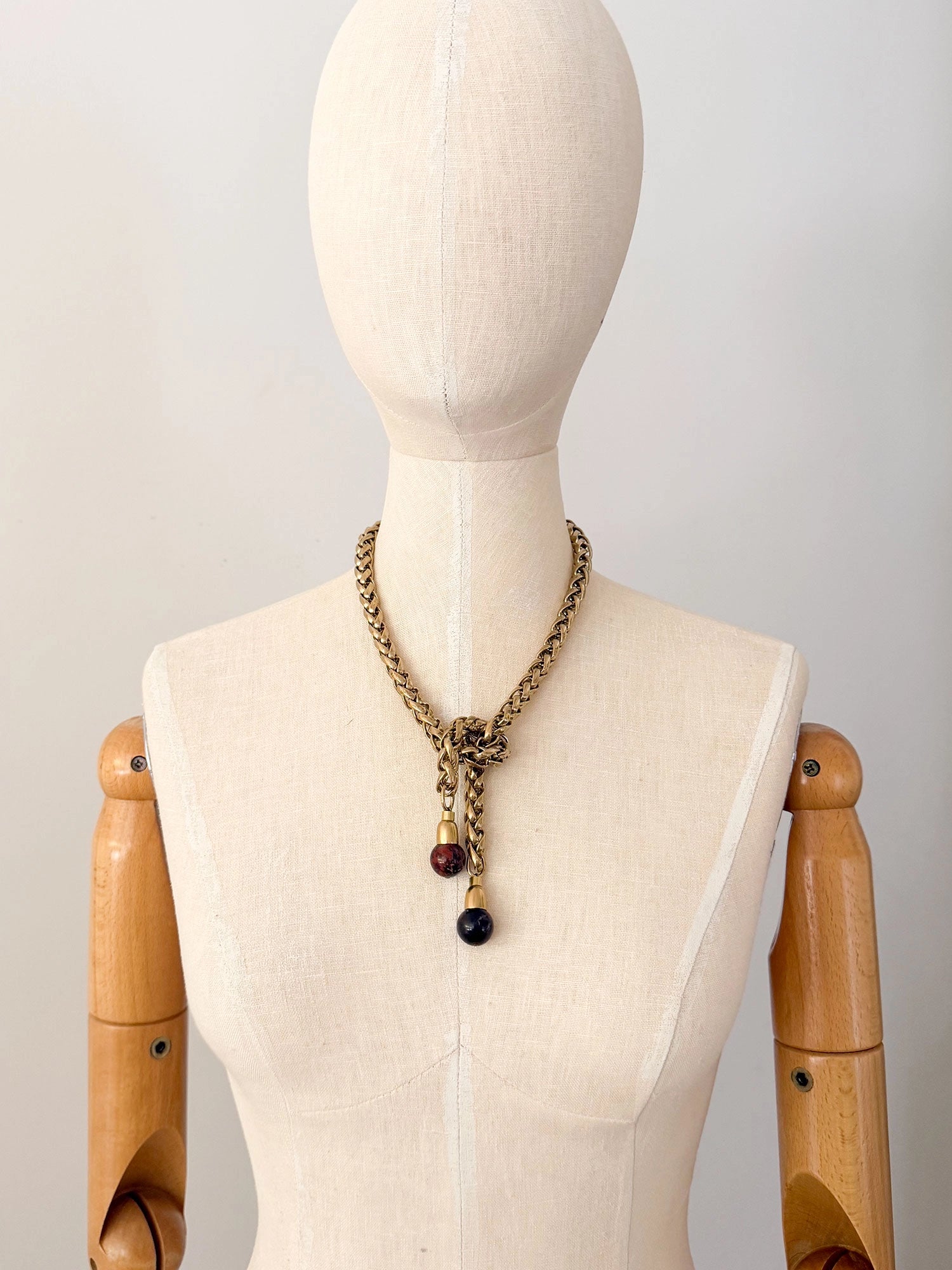 A brass chain lariat necklace knotted with two red jasper bead tassels by Canadian jewelry designer Michelle Ross