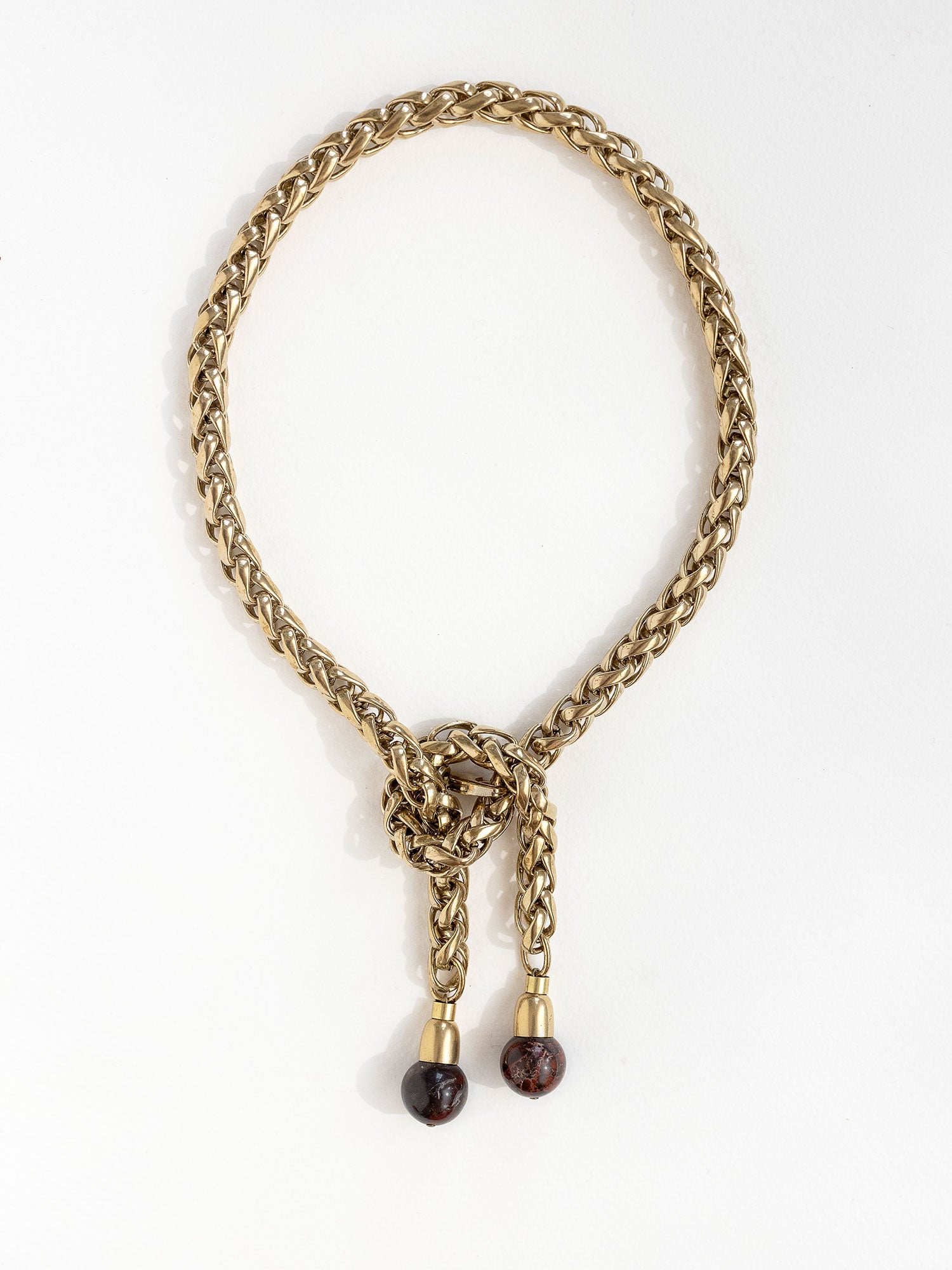 A brass chain lariat necklace with a knotted center detail and two red jasper bead tassels by Canadian jewelry designer Michelle Ross