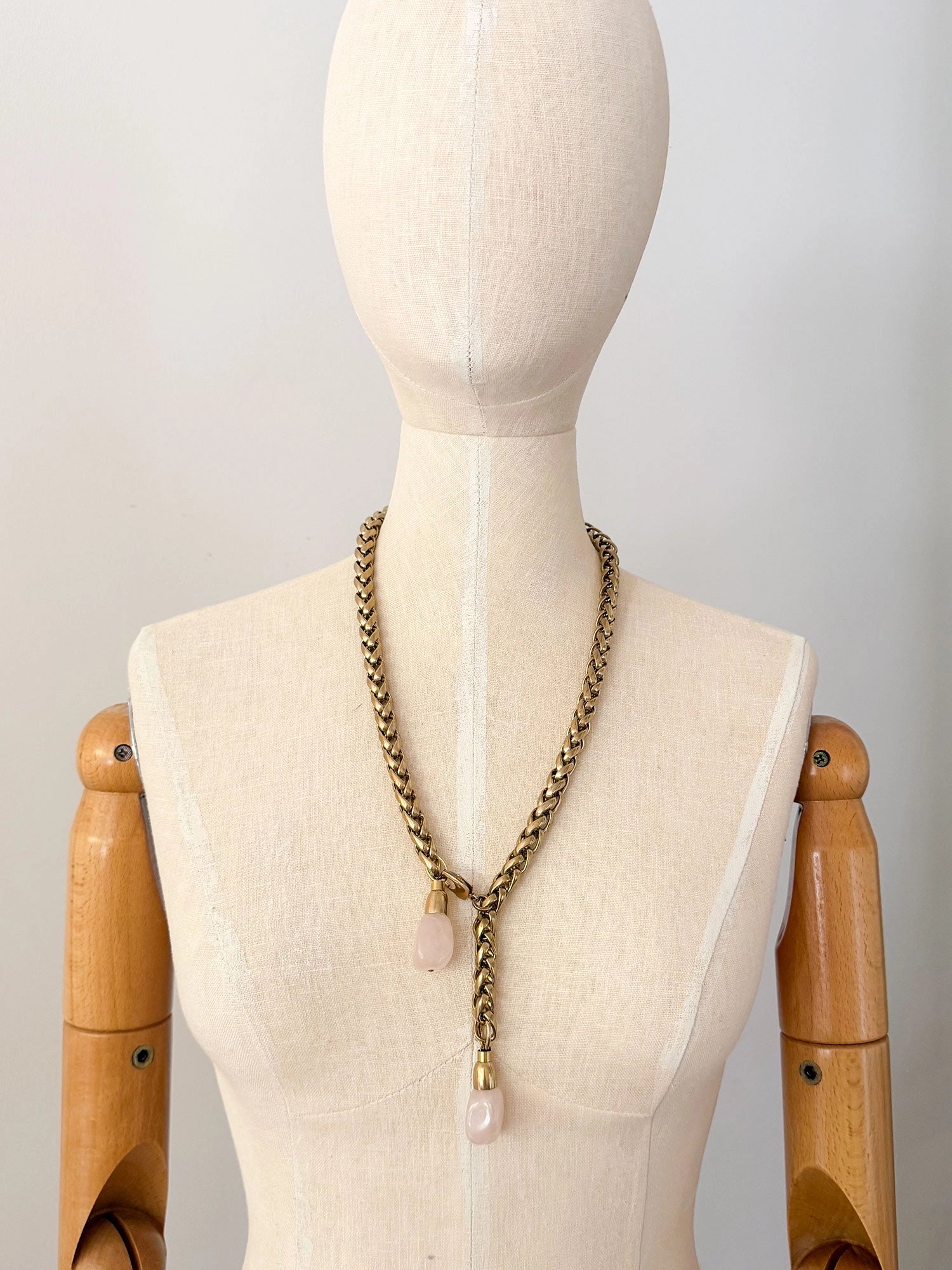 A brass chain lariat necklace knotted with two dangling light pink rose quartz teardrop-shaped beads at the bottom by Canadian jewelry designer Michelle Ross