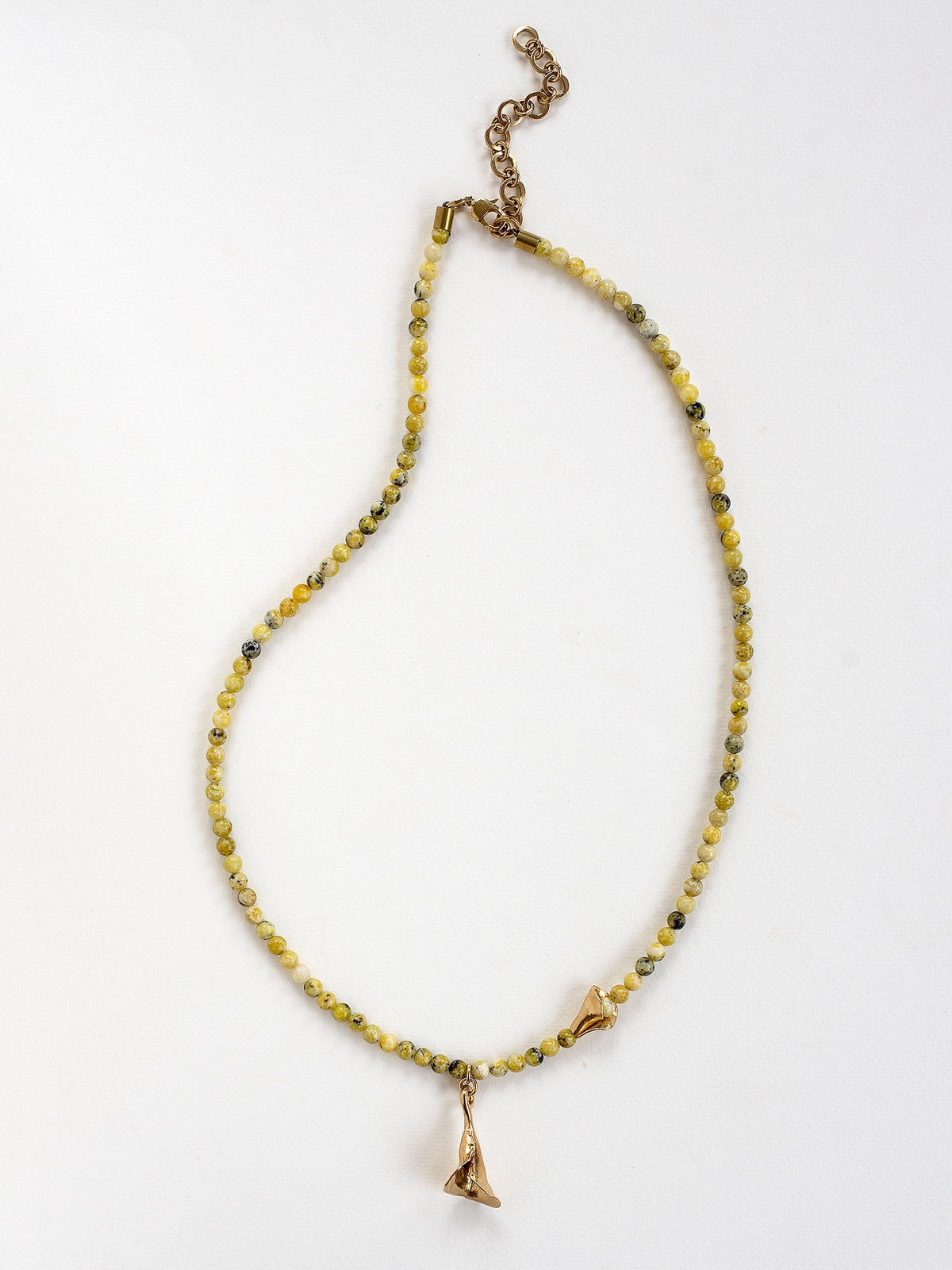 a serpentine quartz beaded necklace with an abstract floral brass pendant by Canadian designer Michelle Ross