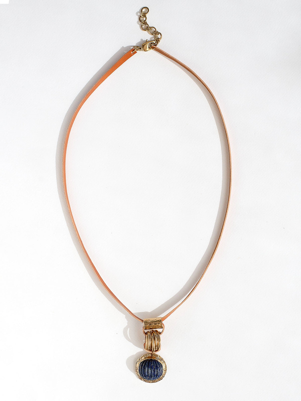 A tan leather long necklace with a brass and lapis lazuli circular pendant by Canadian jewelry designer Michelle Ross