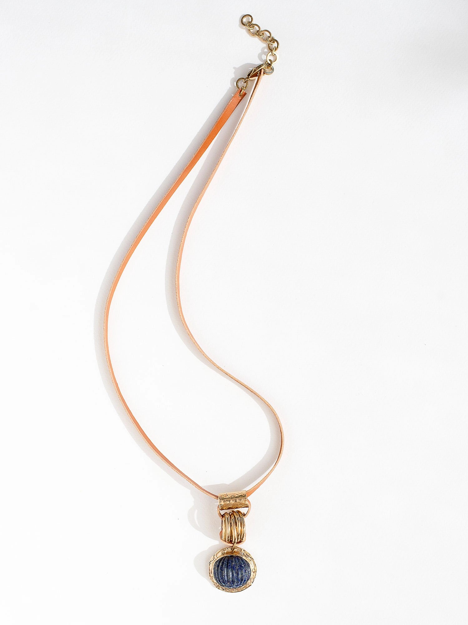 A tan leather long necklace with a brass and lapis lazuli circular pendant by Canadian jewelry designer Michelle Ross