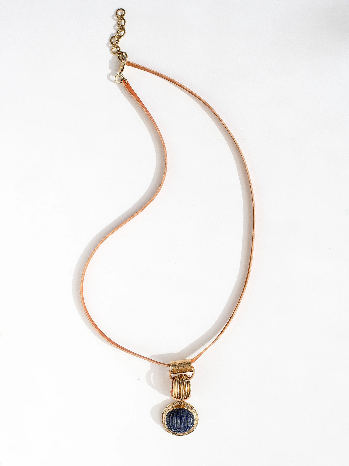 A tan leather long necklace with a brass and lapis lazuli circular pendant by Canadian jewelry designer Michelle Ross