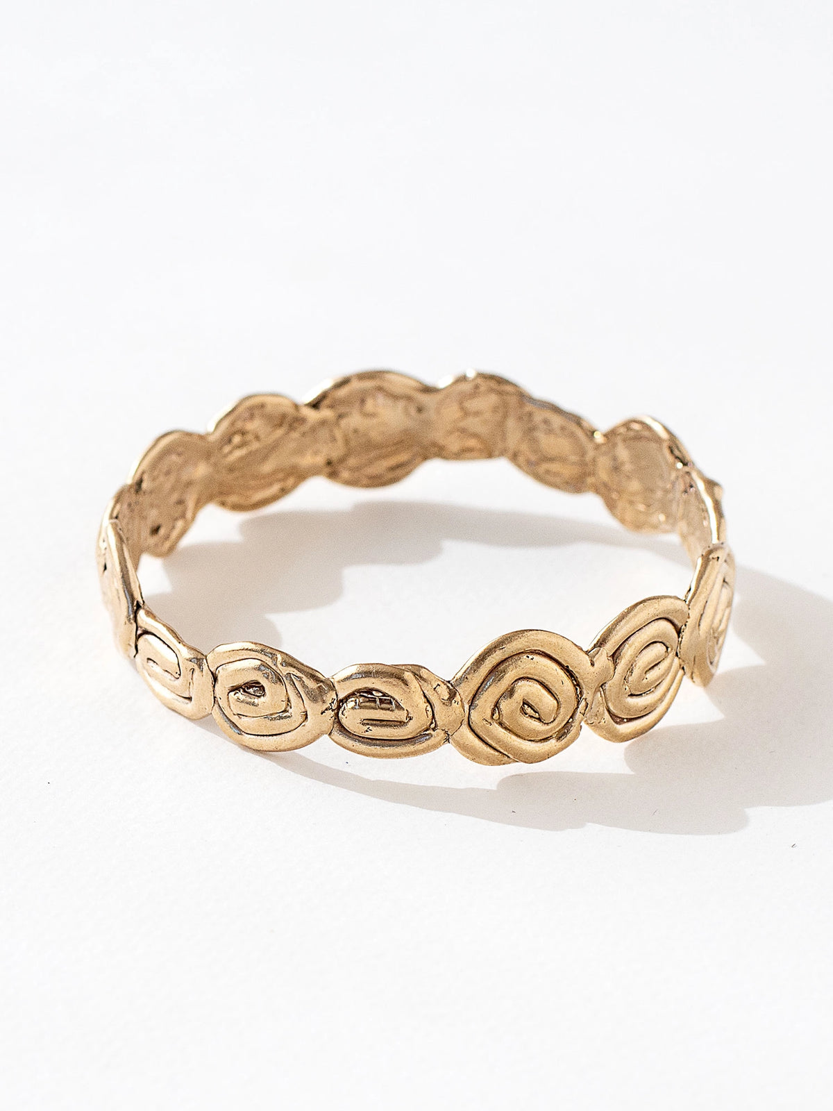A solid brass bangle bracelet with swirl hand-formed details by Canadian jewelry designer Michelle Ross