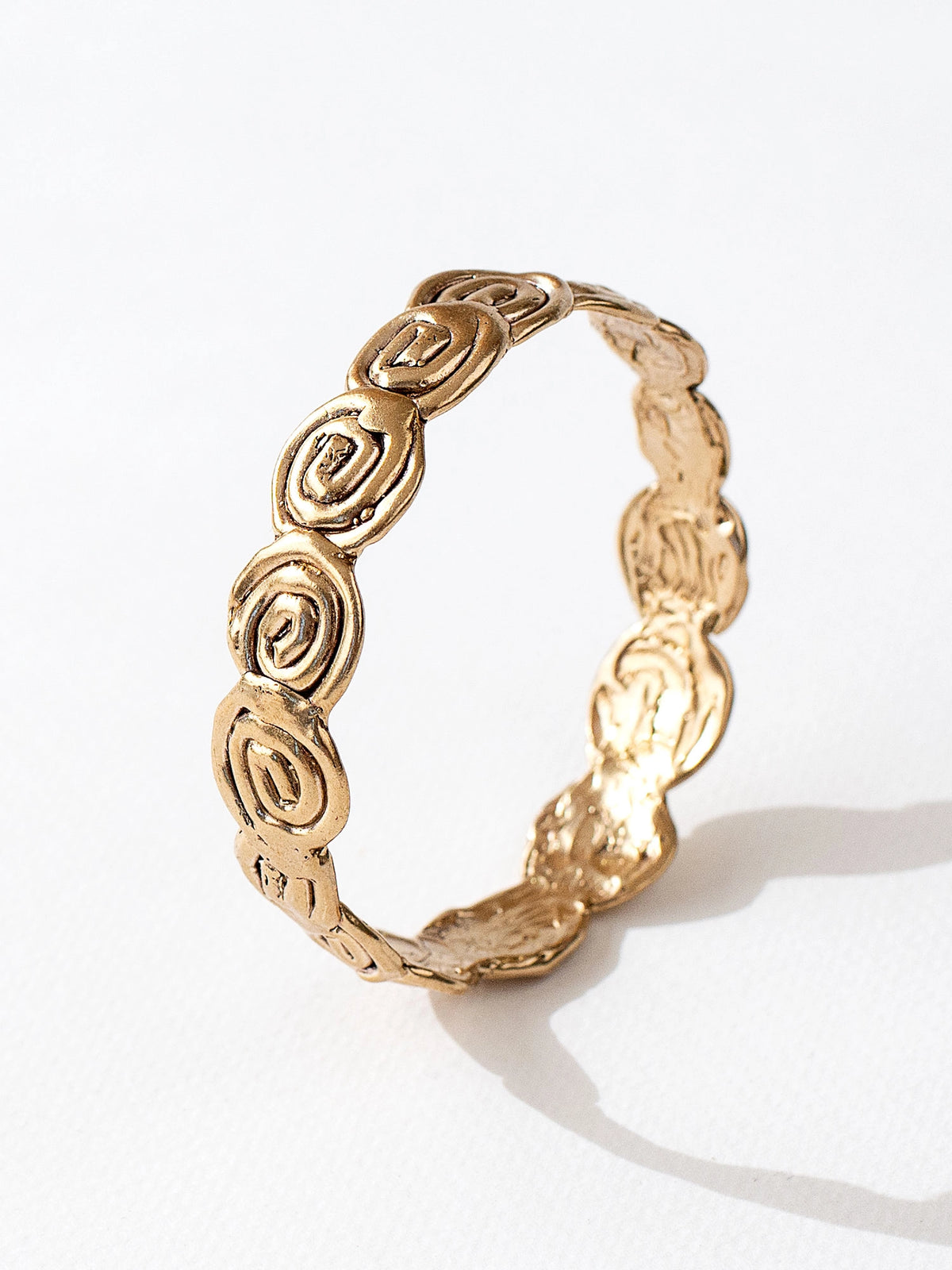 A solid brass bangle bracelet with swirl hand-formed details by Canadian jewelry designer Michelle Ross