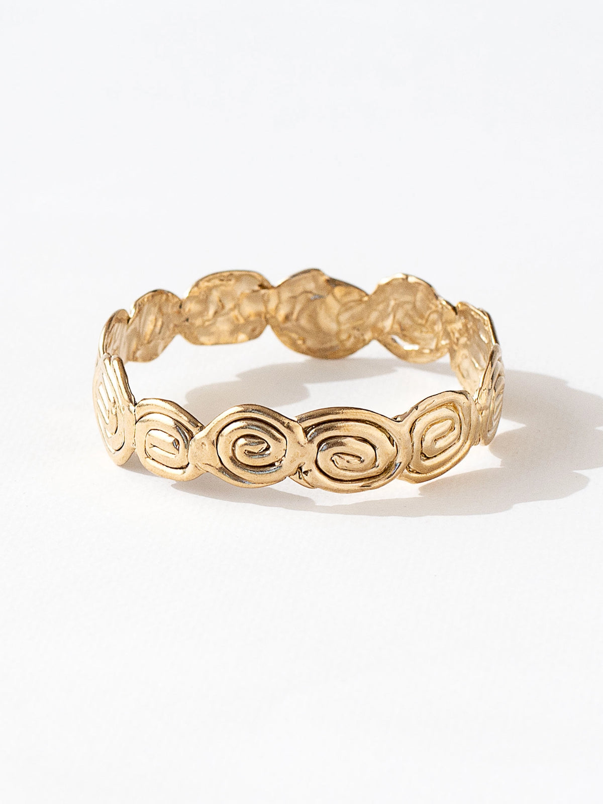 A solid brass bangle bracelet with swirl hand-formed details by Canadian jewelry designer Michelle Ross