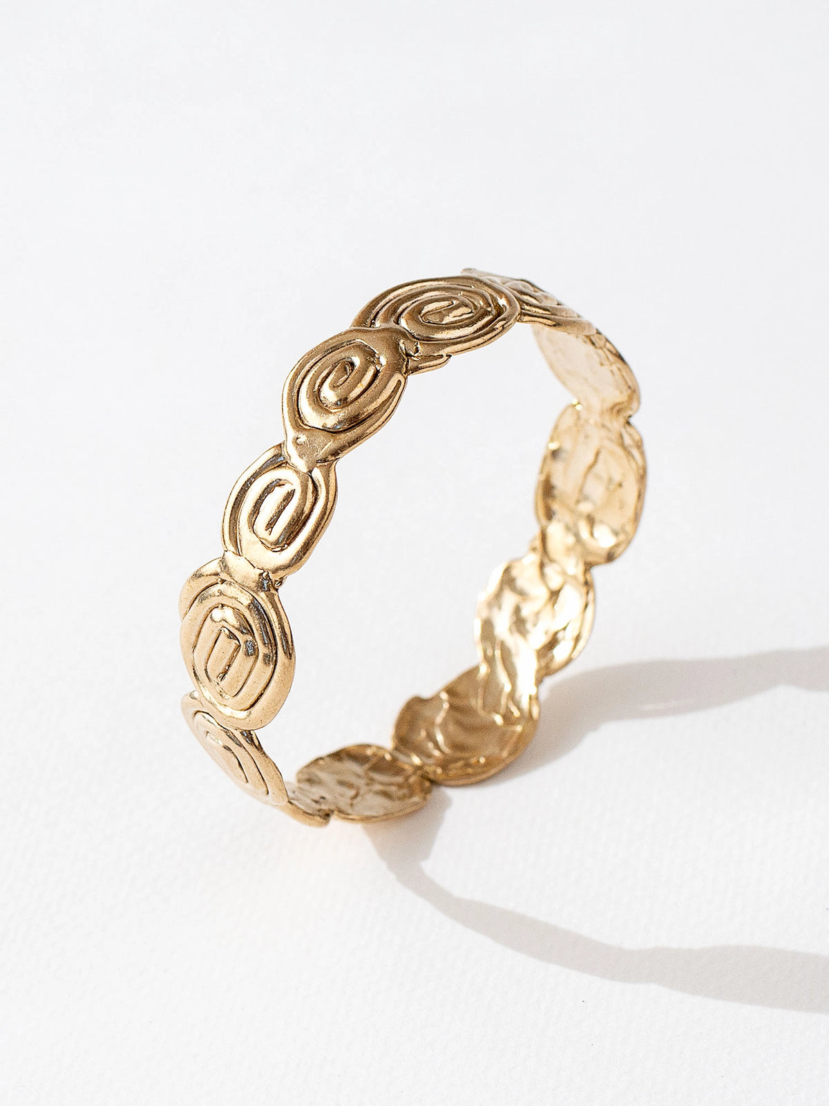 A solid brass bangle bracelet with swirl hand-formed details by Canadian jewelry designer Michelle Ross