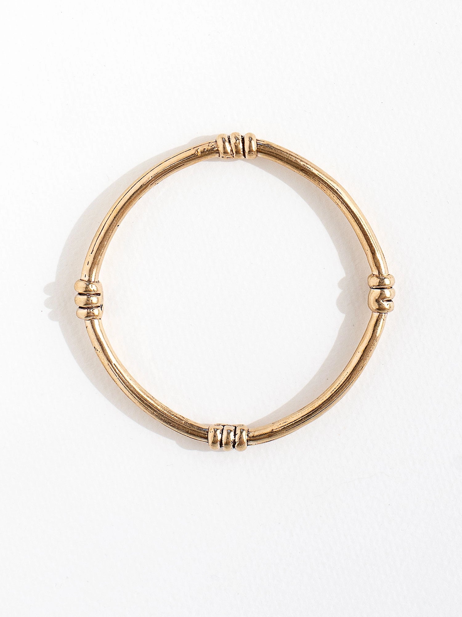 A solid brass bangle with scroll details by contemporary jewelry designer Michelle Ross