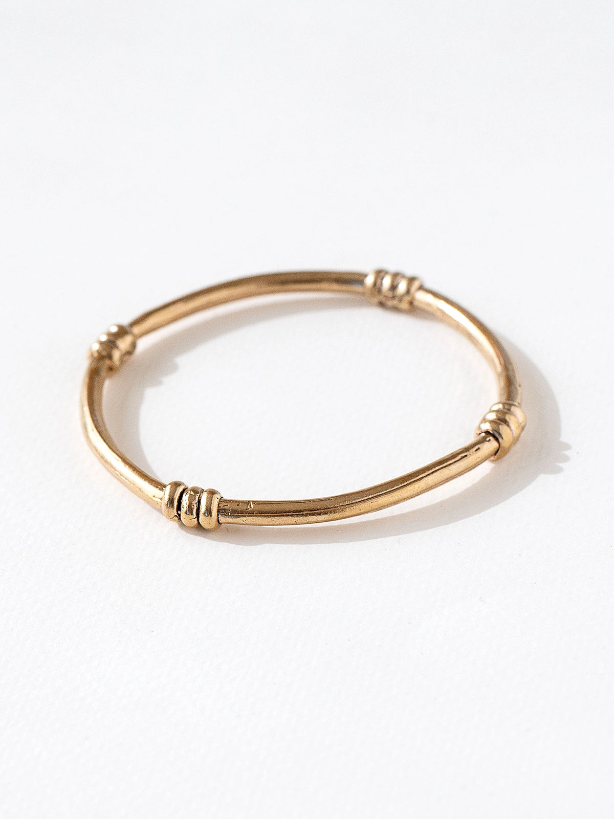 A solid brass bangle with scroll details by contemporary jewelry designer Michelle Ross