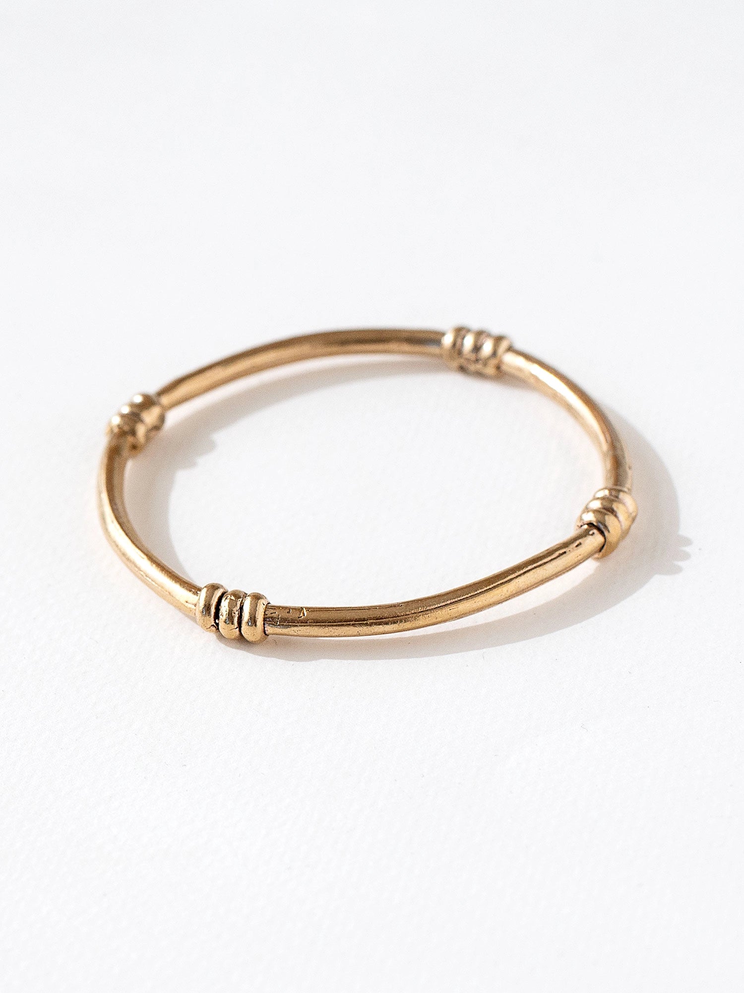 A solid brass bangle with scroll details by contemporary jewelry designer Michelle Ross
