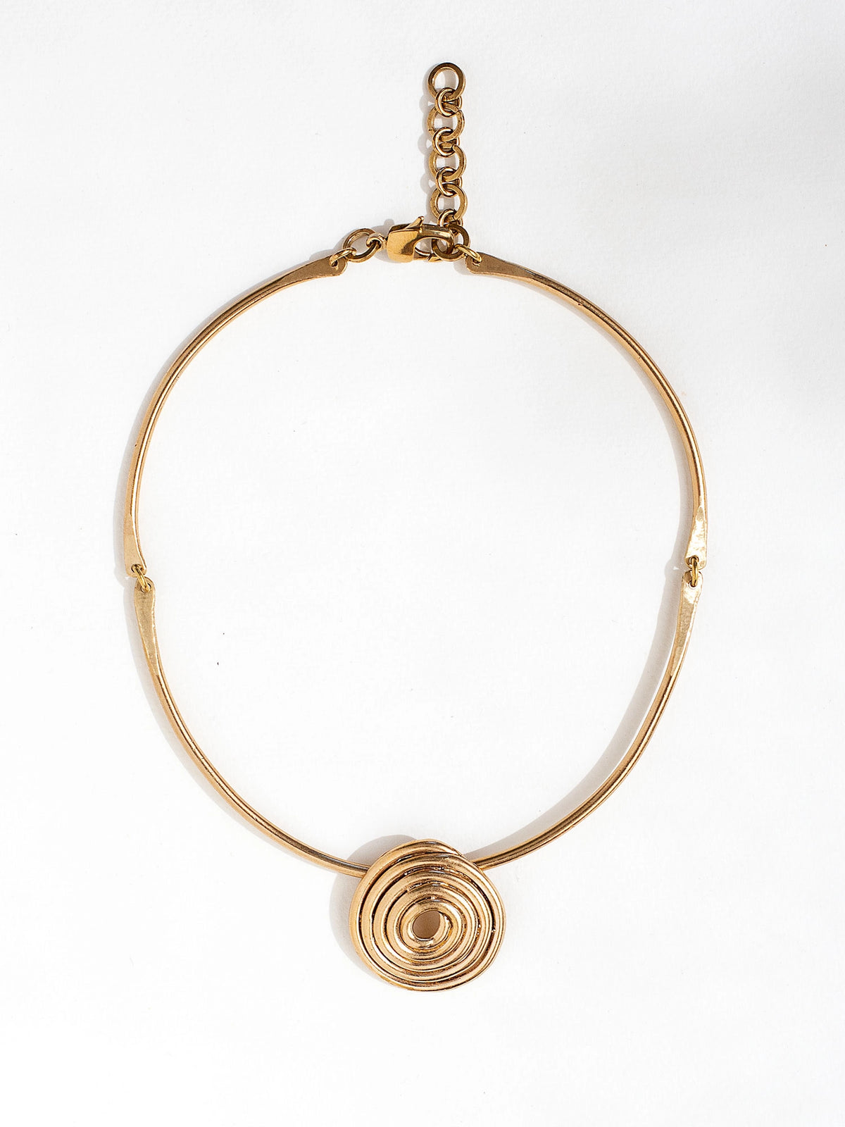 A solid brass collar necklace with a large circular spiral pendant by Canadian jewelry designer Michelle Ross