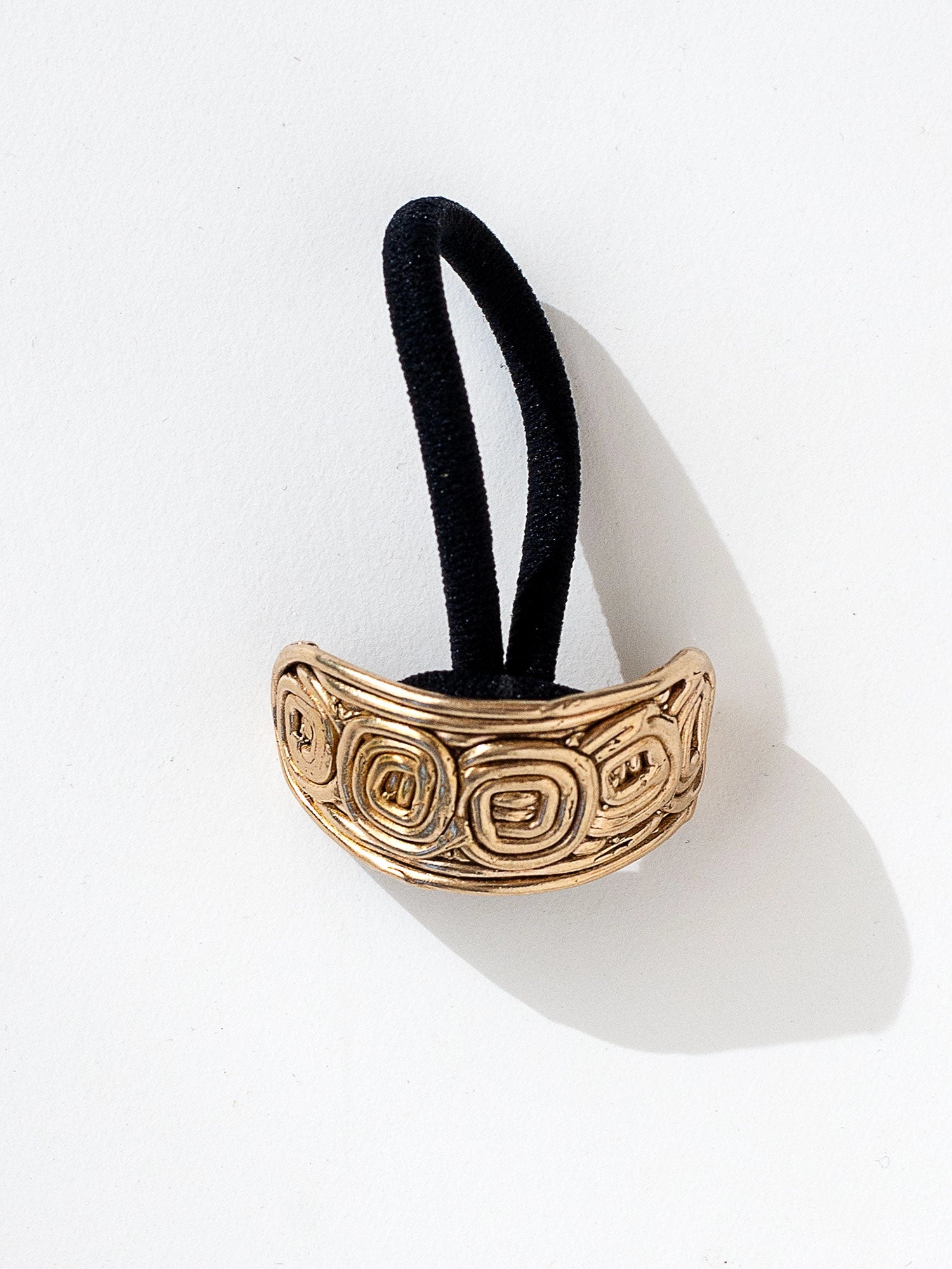 A brass solid hair tie with spiral scroll detail by Canadian jewelry designer Michelle Ross