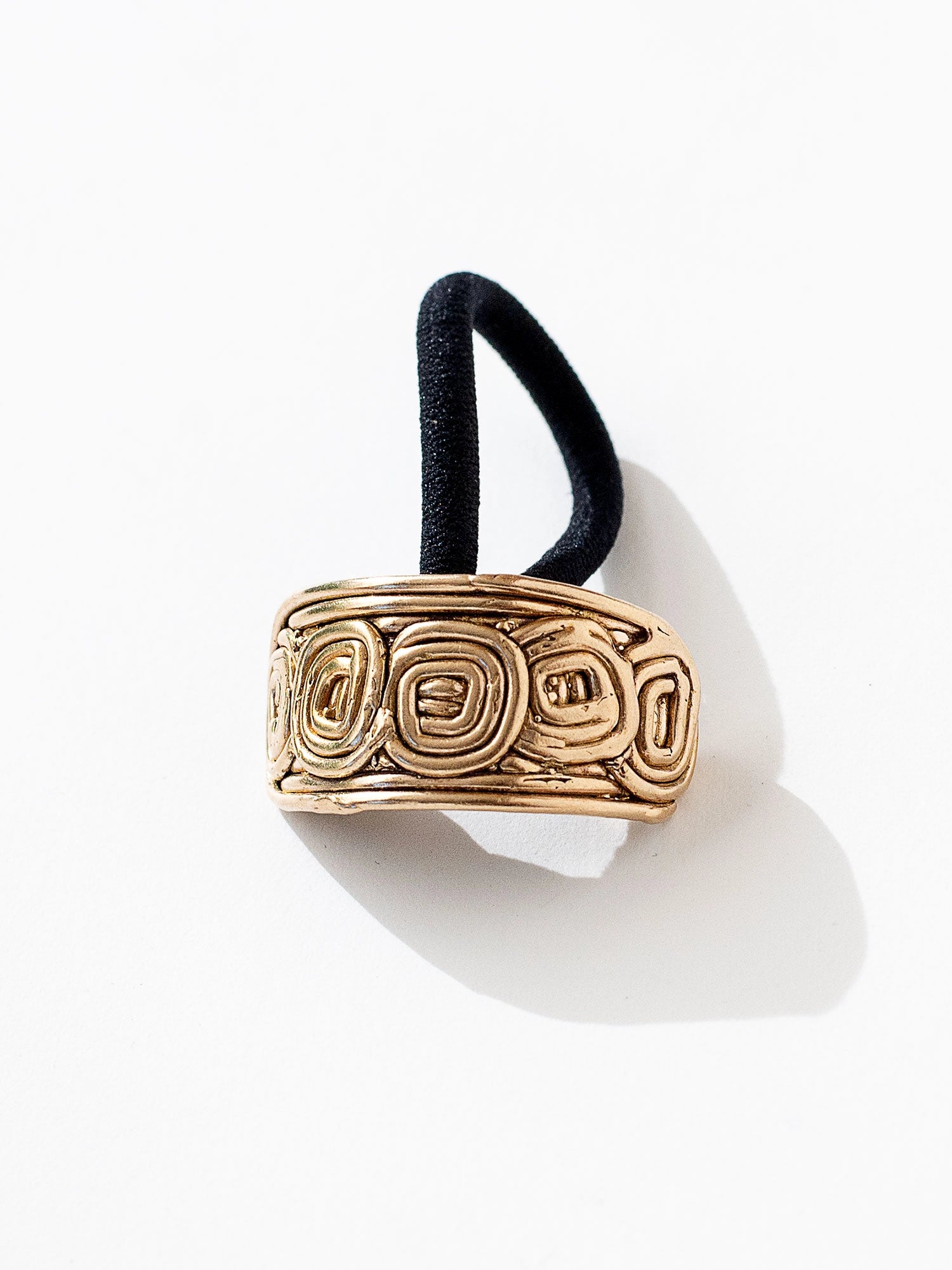 A brass solid hair tie with spiral scroll detail by Canadian jewelry designer Michelle Ross