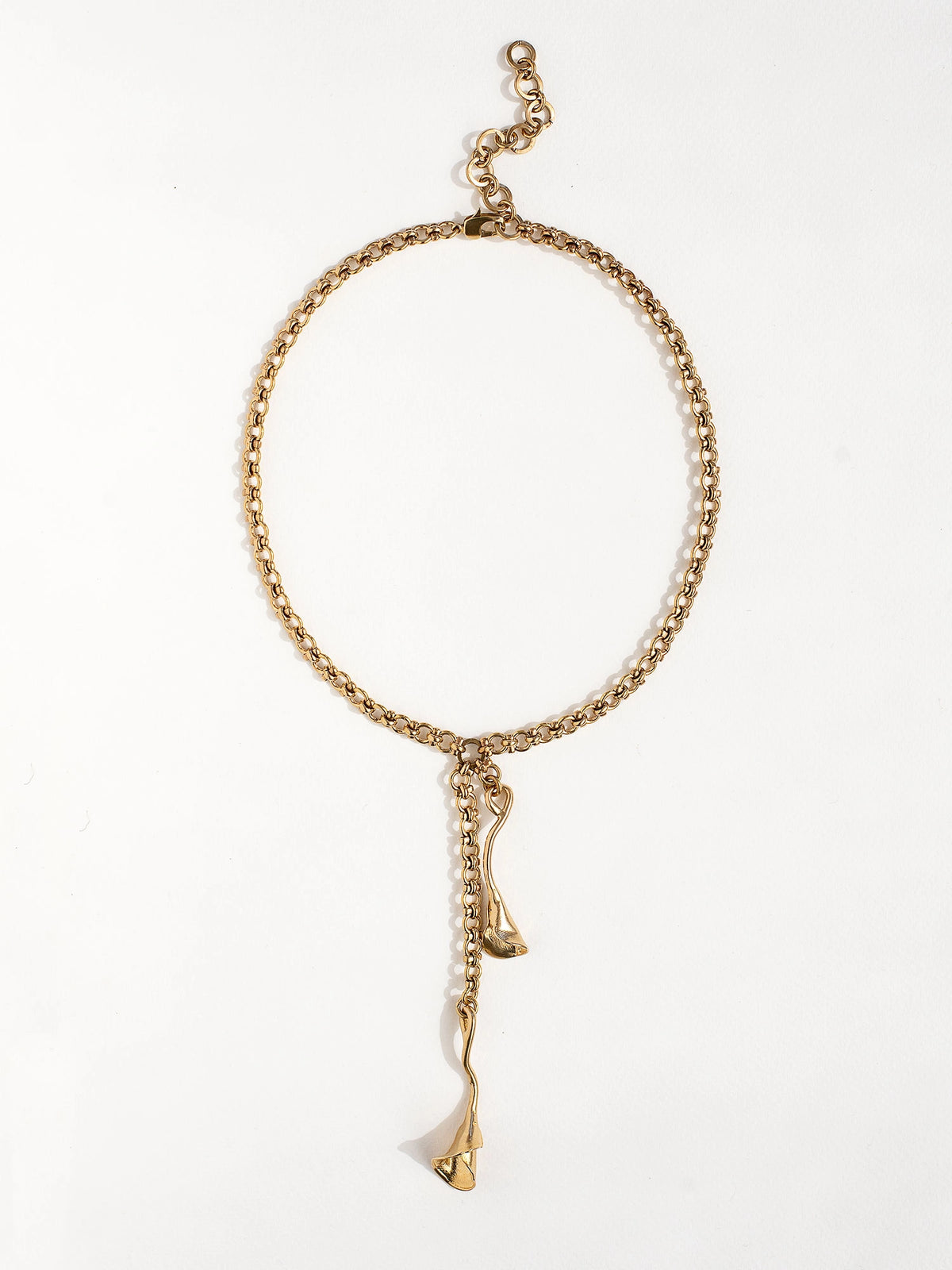 A woman wears a brass chain lariat necklace with sculptural floral pendant details by Canadian jewelry designer Michelle Ross