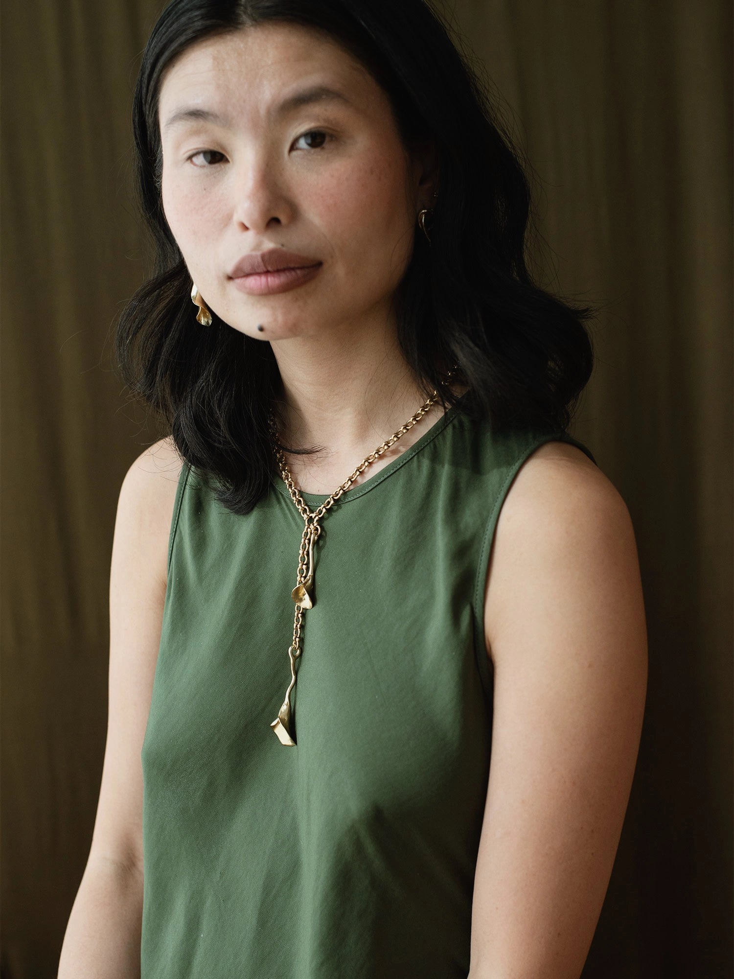 woman wearing abstract floral brass earrings and brass chain lariat necklace with abstract floral brass pendant by Canadian jeweller Michelle Ross