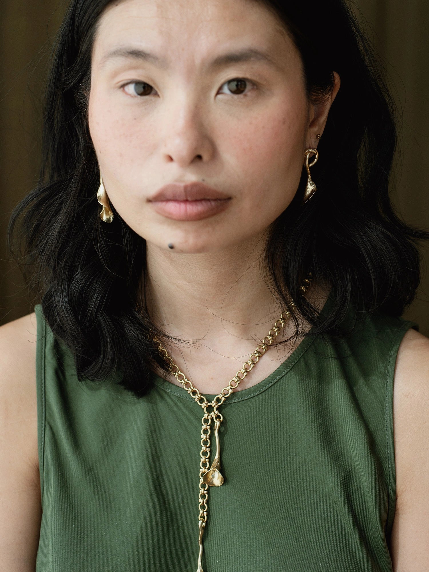 woman wearing abstract floral brass earrings and brass chain lariat necklace by Canadian jeweller Michelle Ross