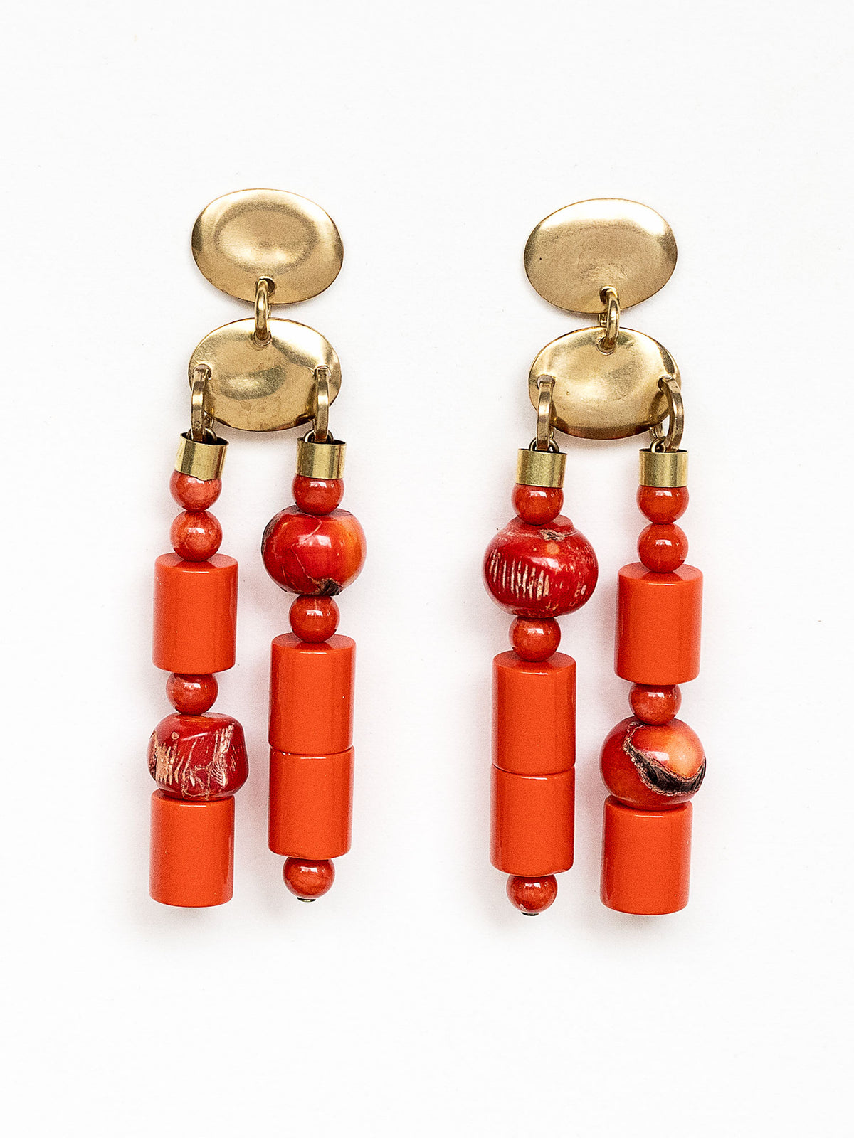 A pair of statement chandelier earrings featuring brass metal discs with vibrant red coral and resin beads by Canadian jewelry designer Michelle Ross