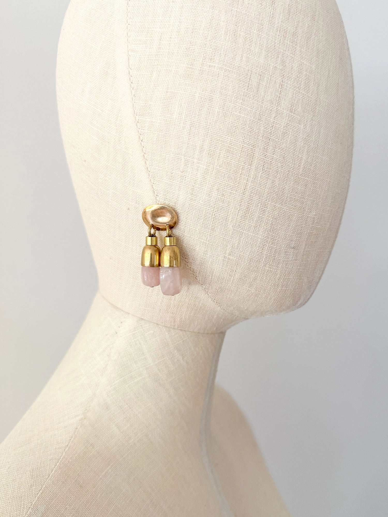 A pair of brass drop earrings with oval posts and two dangling pink stone rose quartz beads by Canadian jewelry designer Michelle Ross