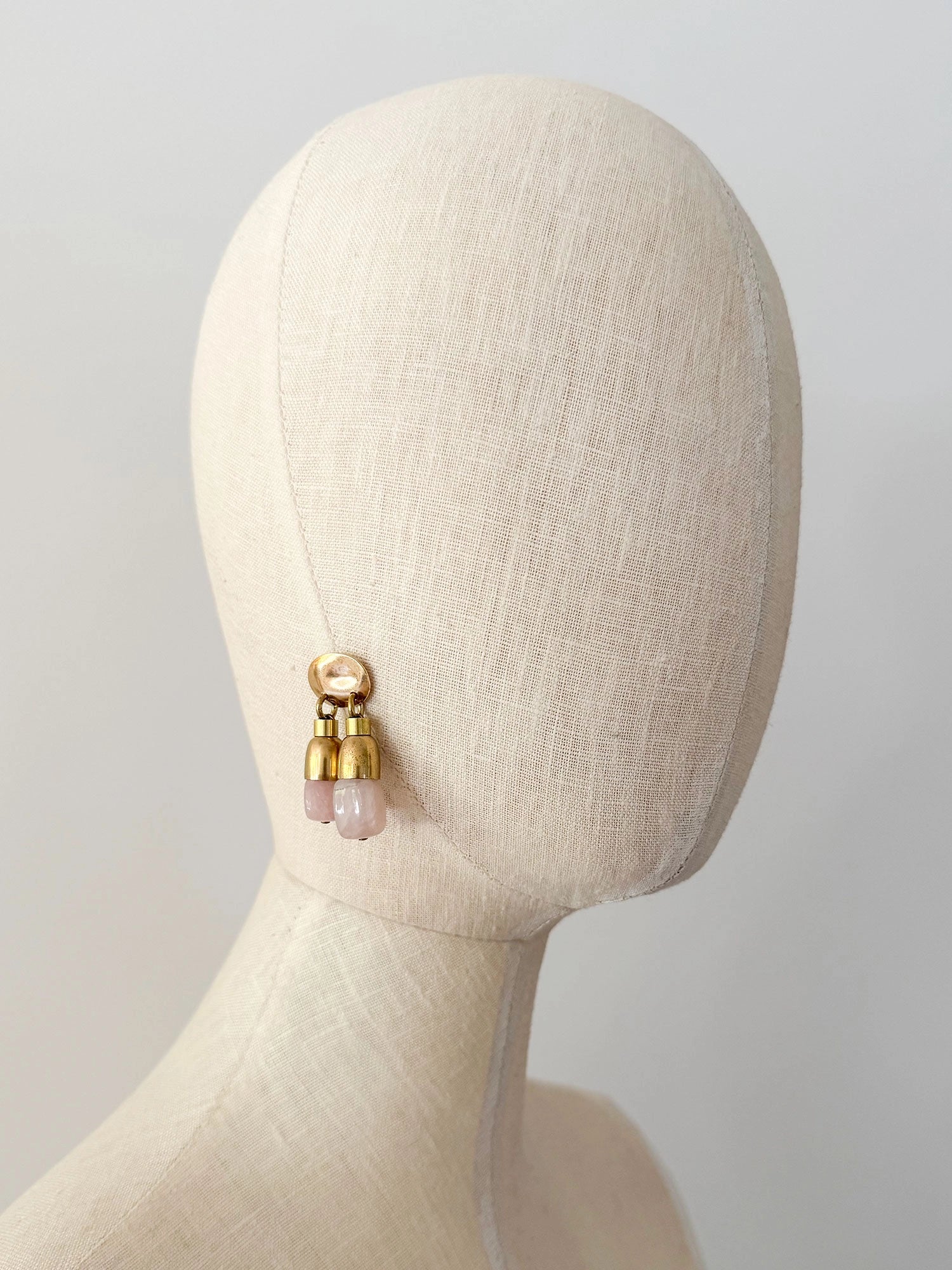 A pair of brass drop earrings with oval posts and two dangling pink stone rose quartz beads by Canadian jewelry designer Michelle Ross
